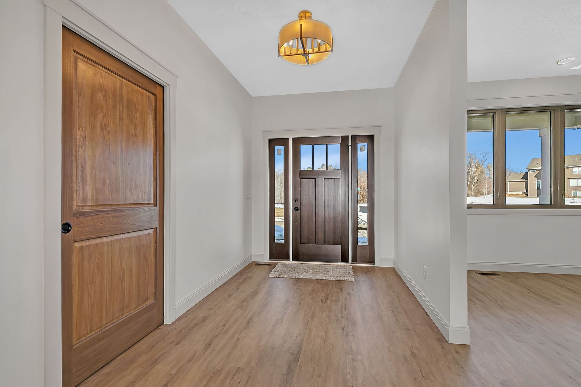 Interior view of a home entryway with wood doors, a light fixture, and windows.