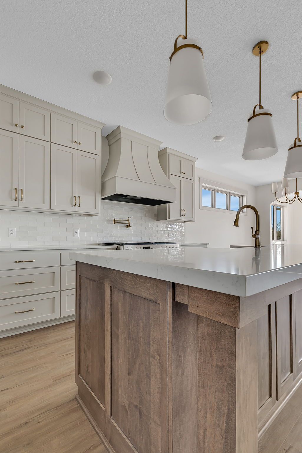 Kitchen with white cabinets, wood island, and pendant lights.