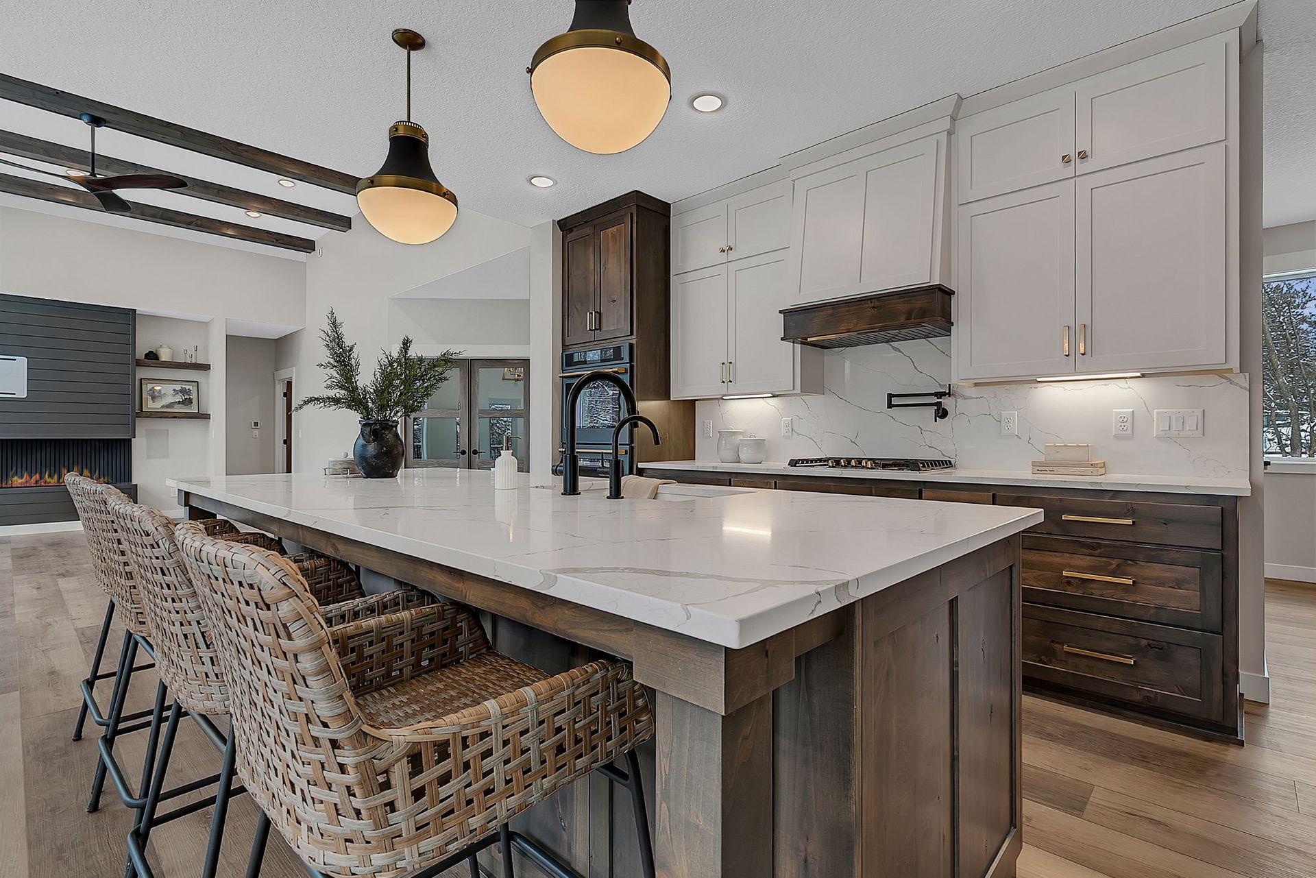 Modern kitchen with a large island, pendant lights, white countertops, and wooden cabinets.