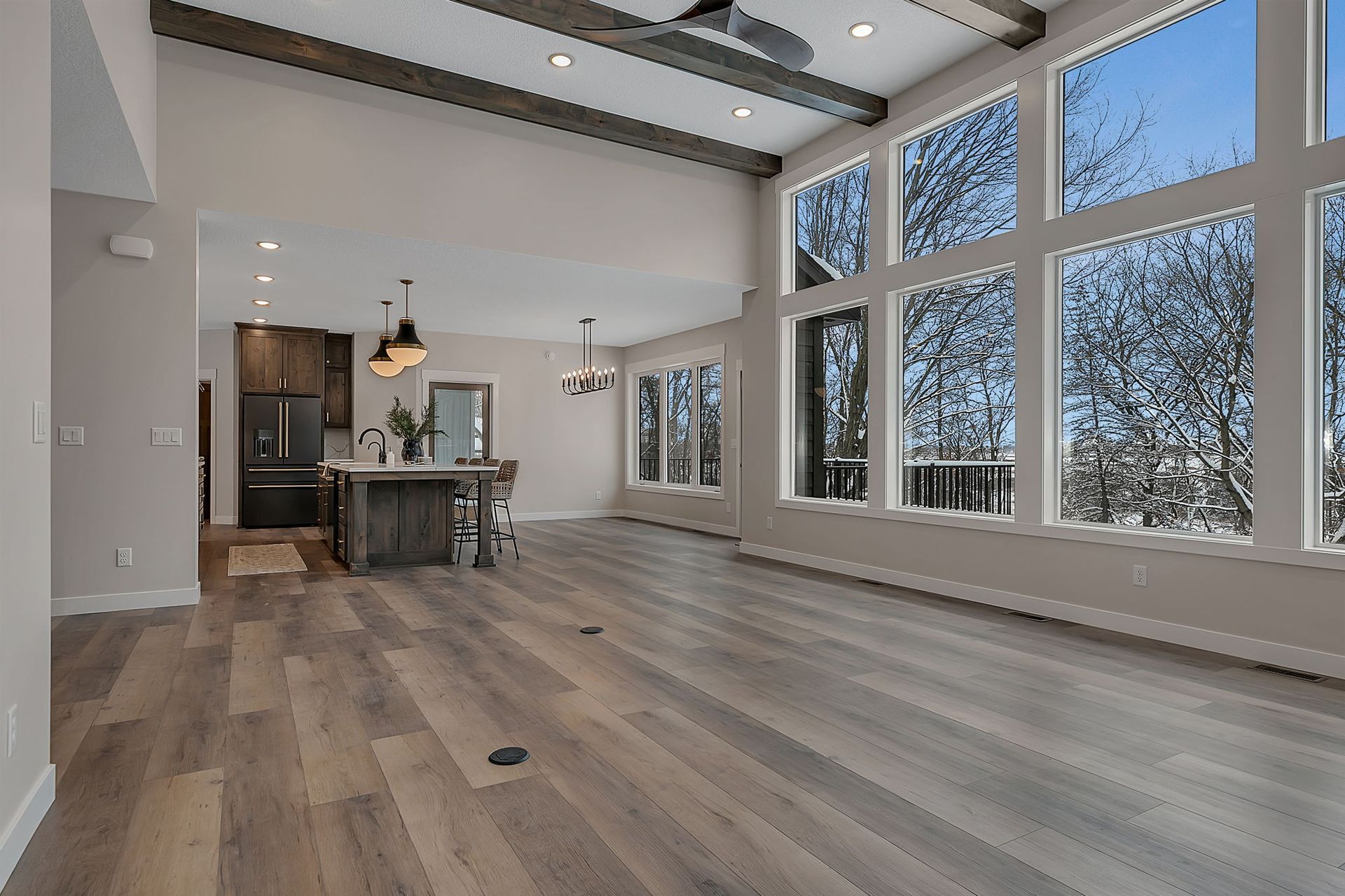 Spacious interior with large windows, hardwood floors, and exposed beams, showcasing a kitchen and living area.