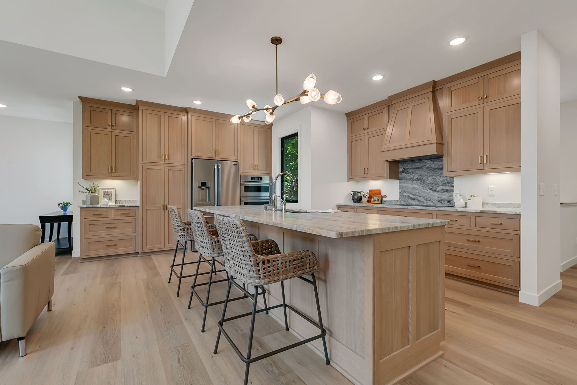 Modern kitchen with light wood cabinets, island seating, stainless appliances, and pendant lighting