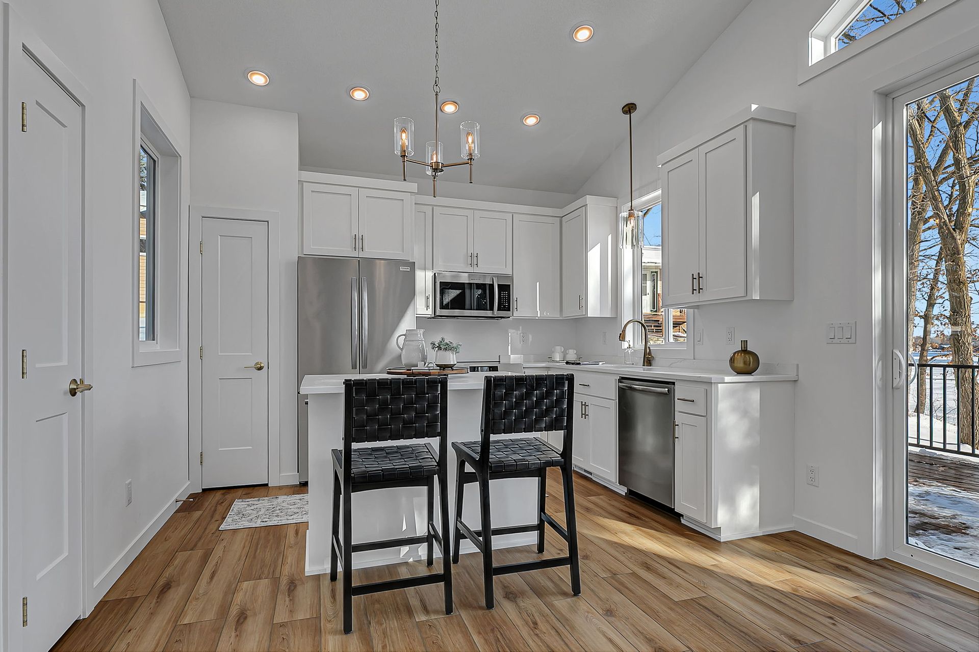 Bright white kitchen with stainless steel appliances, breakfast bar, and outdoor view.