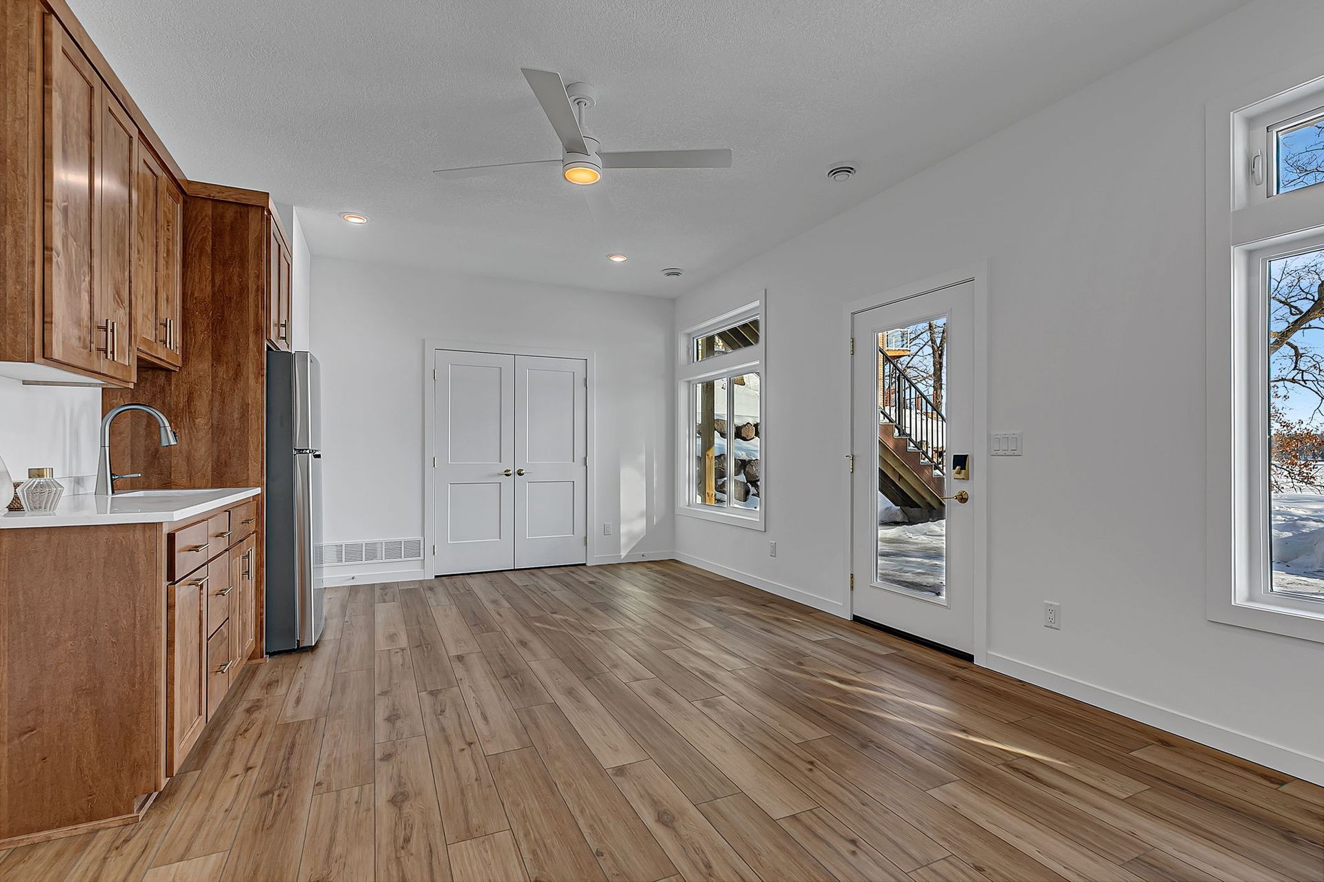 Interior view: Kitchen area with wooden cabinets, light-colored walls, and a door leading outside.
