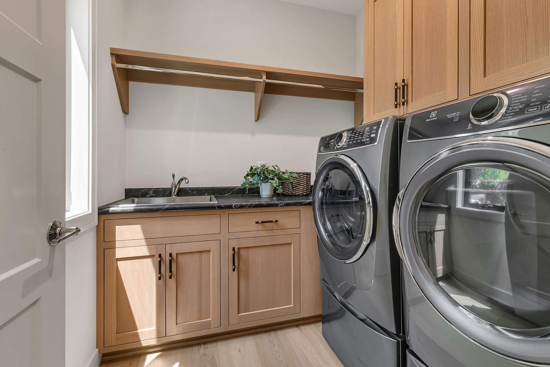 Laundry room with front-loading washer and dryer, wood cabinets, countertop, and open shelves