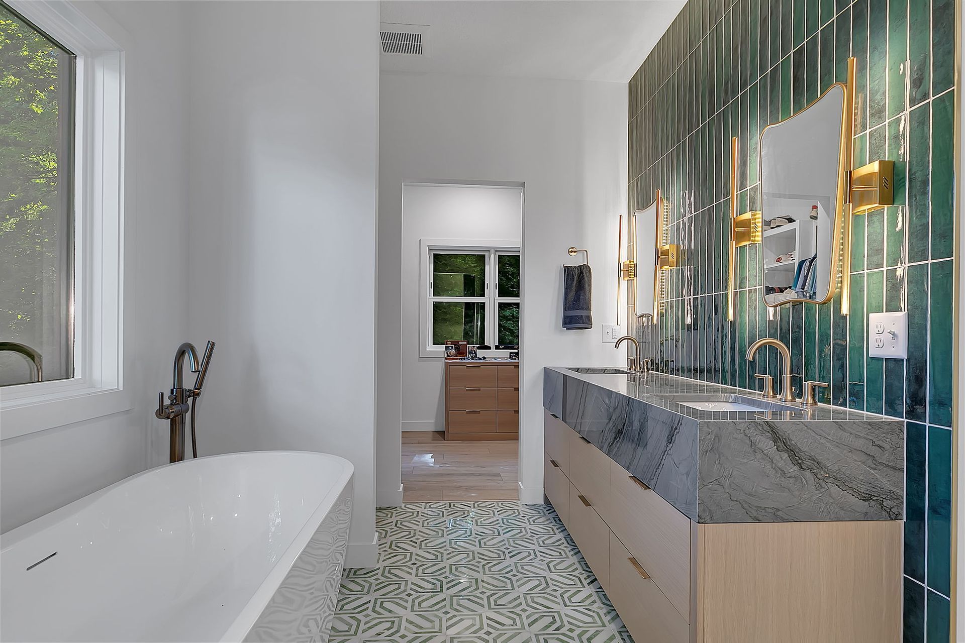 Modern bathroom with freestanding tub, marble vanity, and green mosaic tile wall