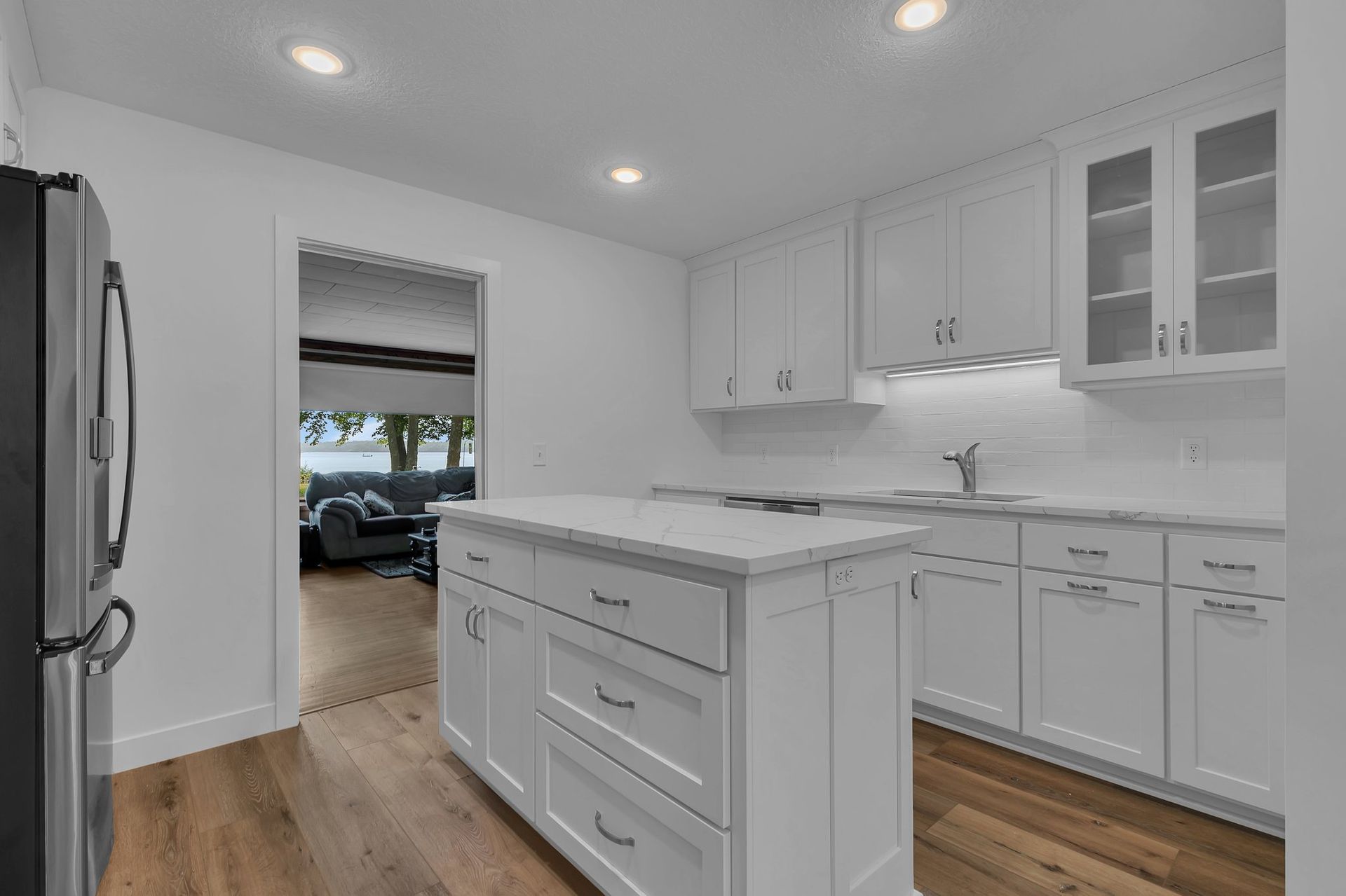 A kitchen with white cabinets and a large island in the middle.