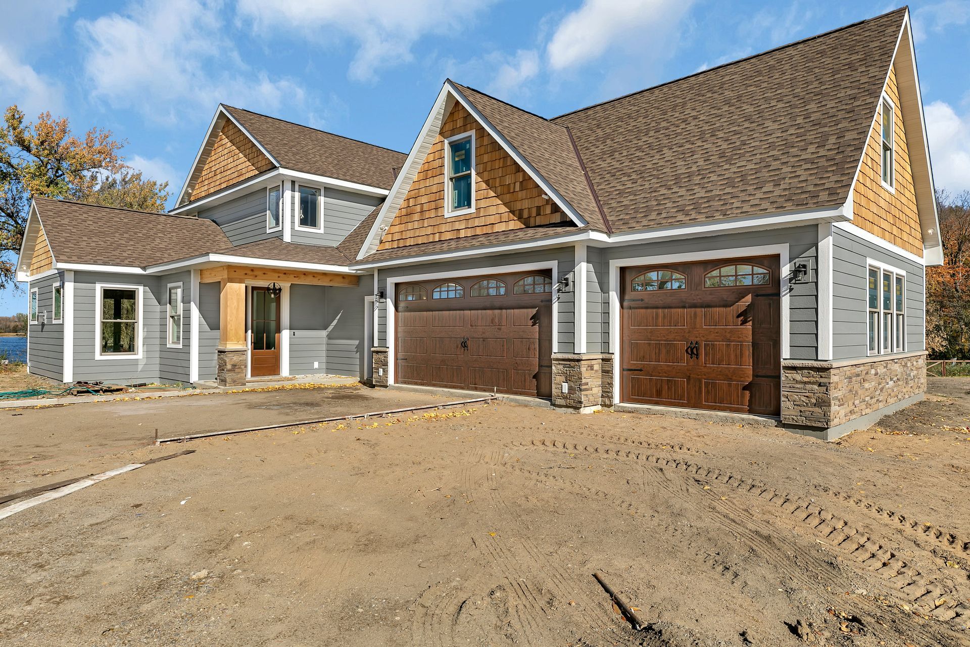A large house with two garage doors is sitting on top of a dirt field.