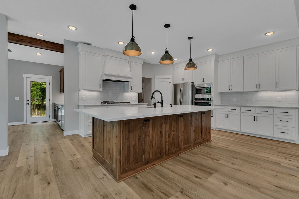 A kitchen with white cabinets and wooden floors and a large island.