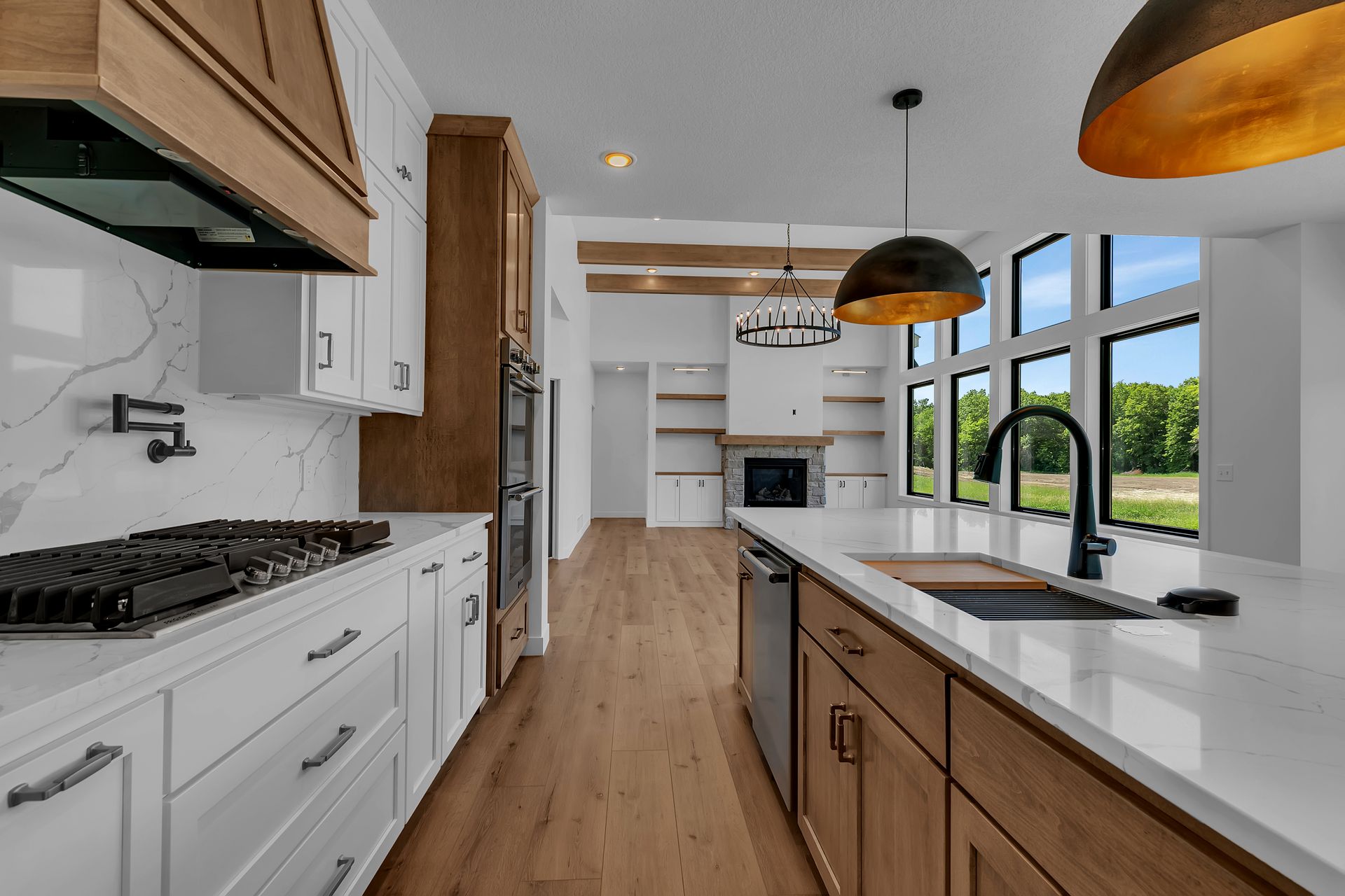 A kitchen with white cabinets and wooden floors and a stove top oven.