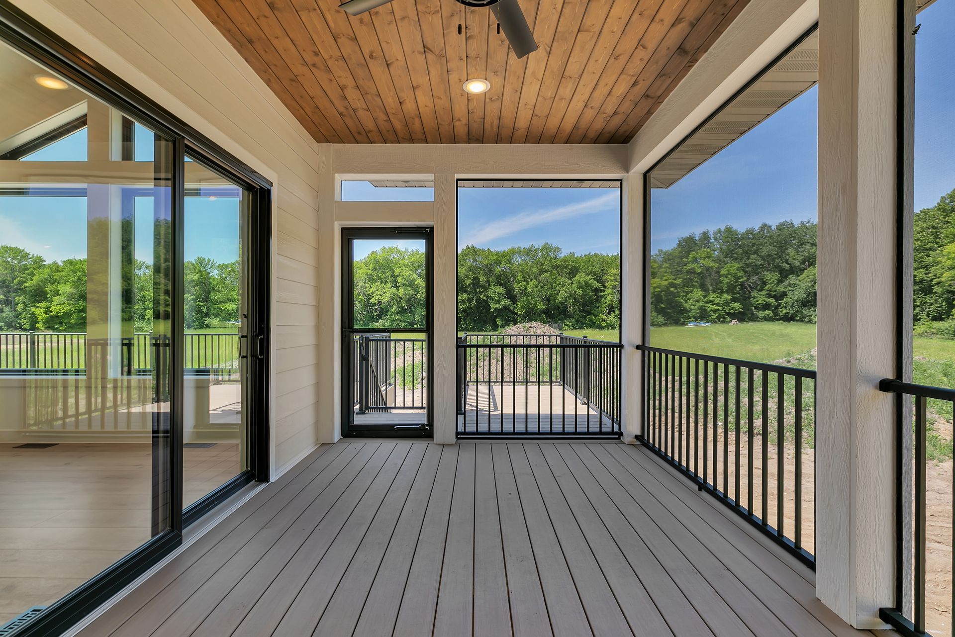 A screened in porch with sliding glass doors and a ceiling fan