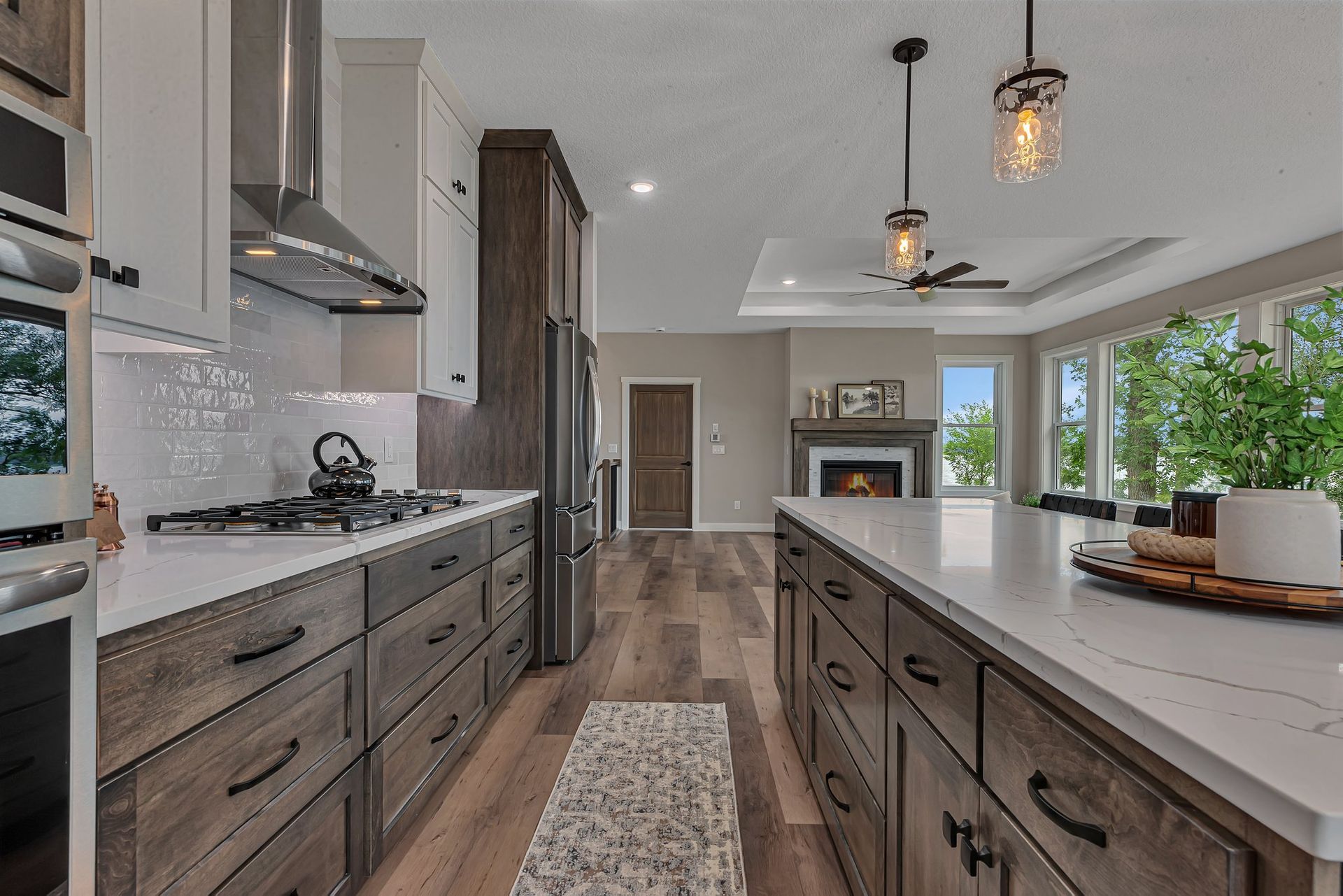 A kitchen with wooden cabinets , white counter tops , stainless steel appliances and a large island.
