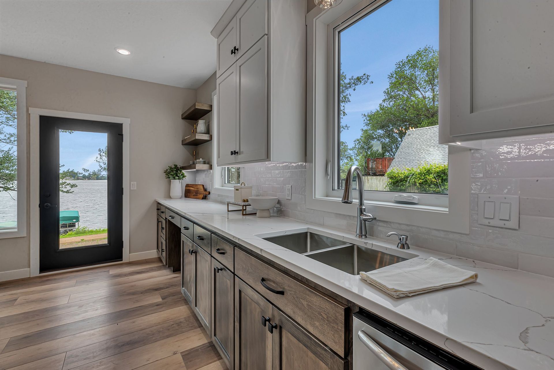 A kitchen with a sink and a window with a view of a lake.