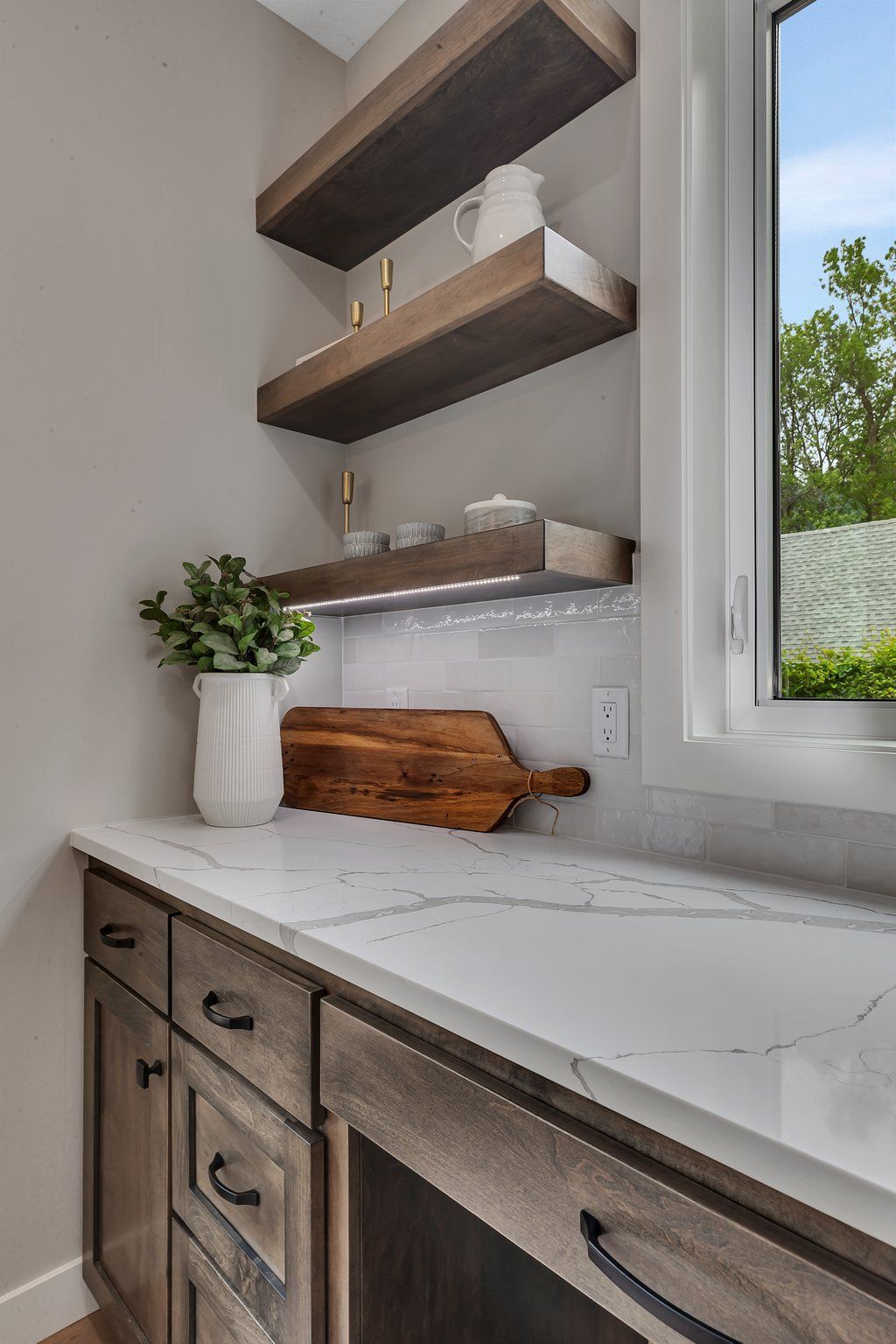 A kitchen with a cutting board on the counter and a window.