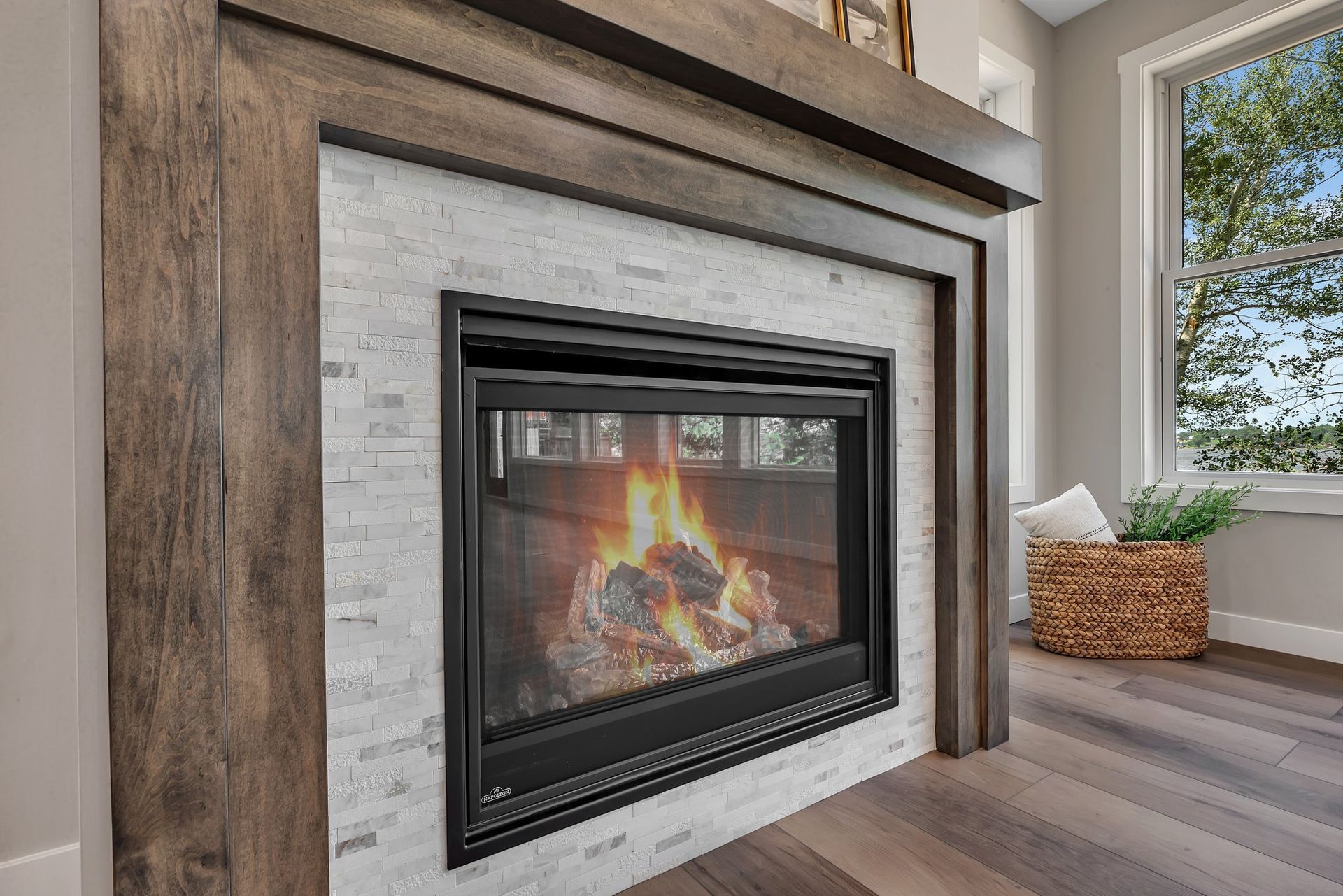 A fireplace in a living room with a wooden mantle and a window.