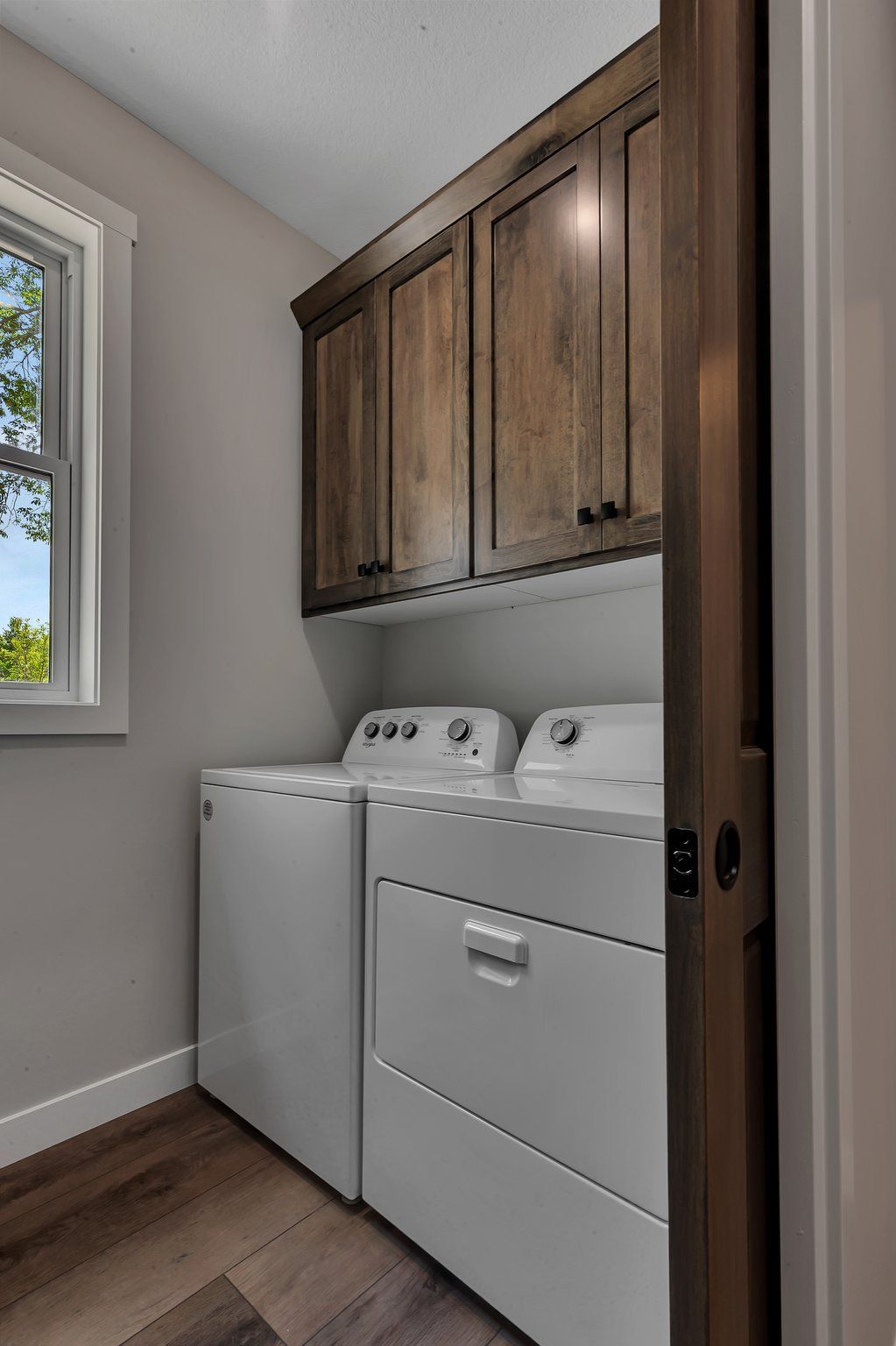 A laundry room with a washer and dryer and wooden cabinets.