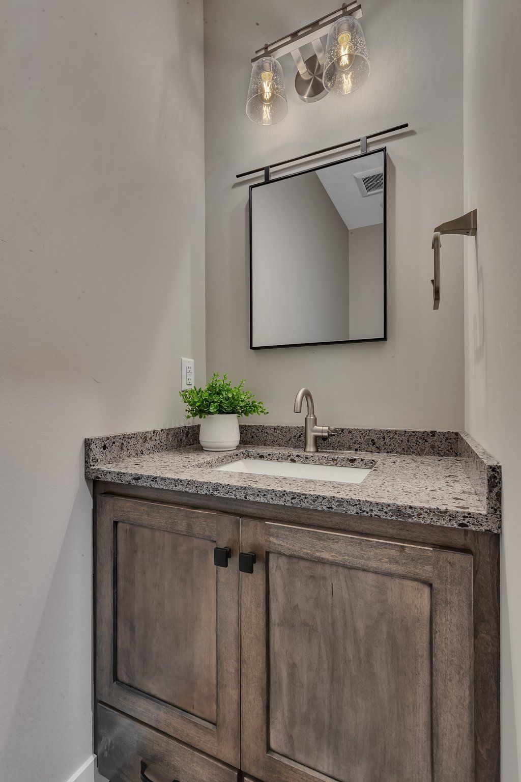 A bathroom with a sink , mirror and light fixture.