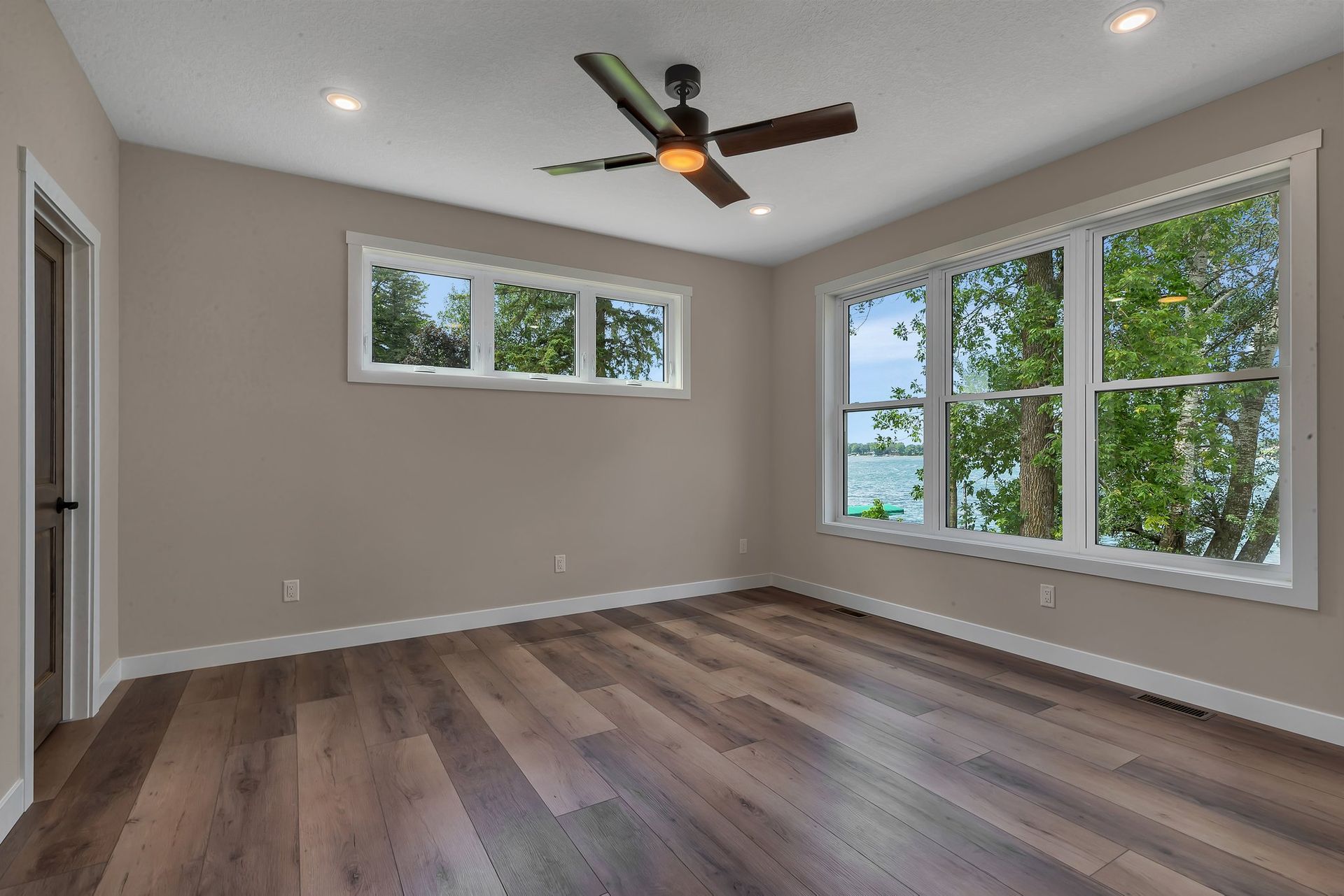 An empty room with hardwood floors and a ceiling fan.