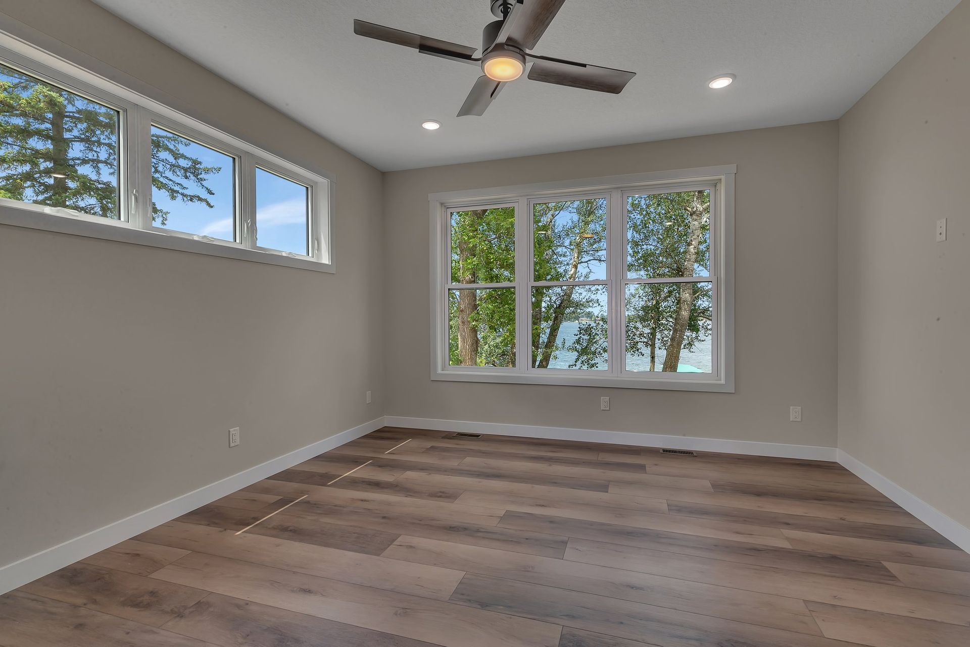 An empty room with hardwood floors and a ceiling fan.