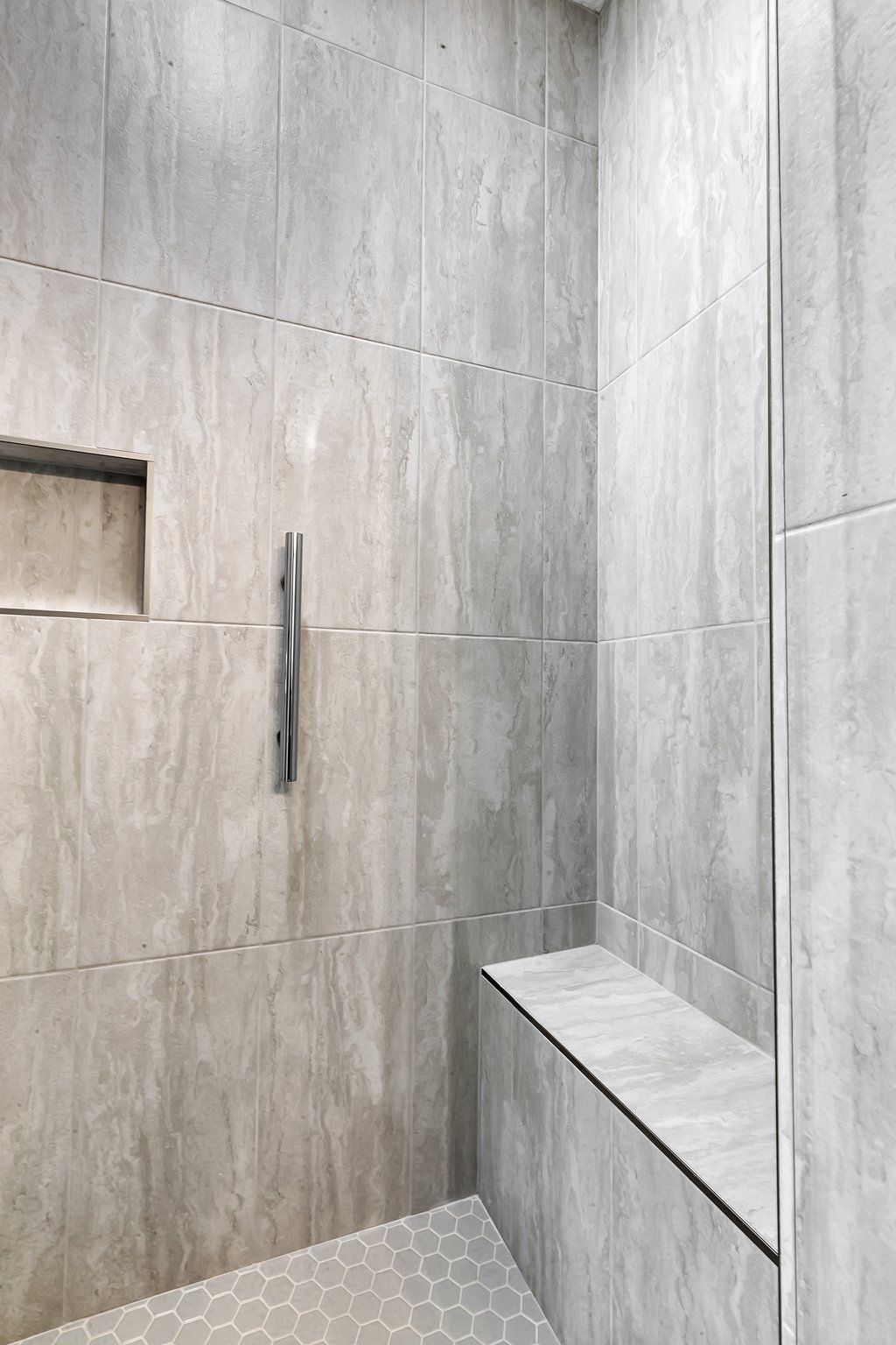 A bathroom with a walk in shower and a bench.