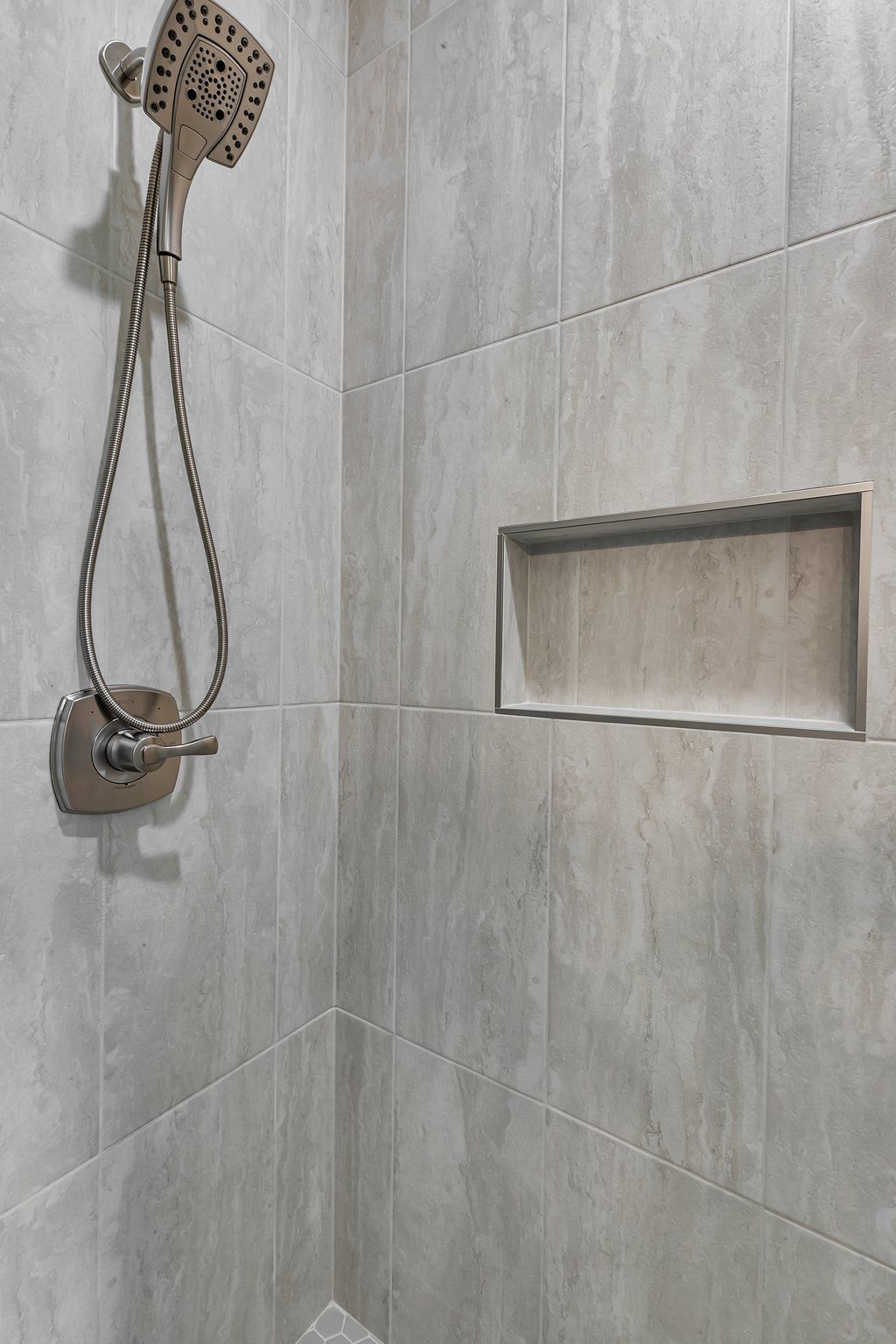 A shower with a shower head and a shelf in the wall.