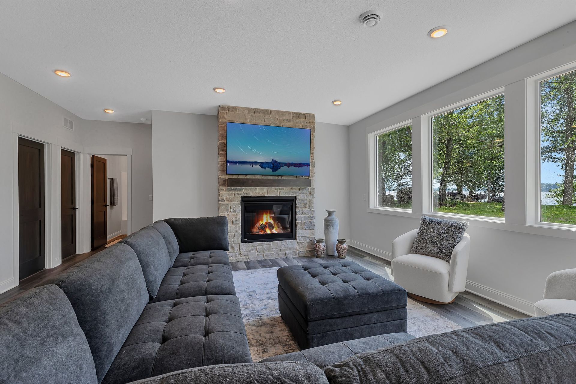 A living room with a couch , chair , ottoman , fireplace and television.