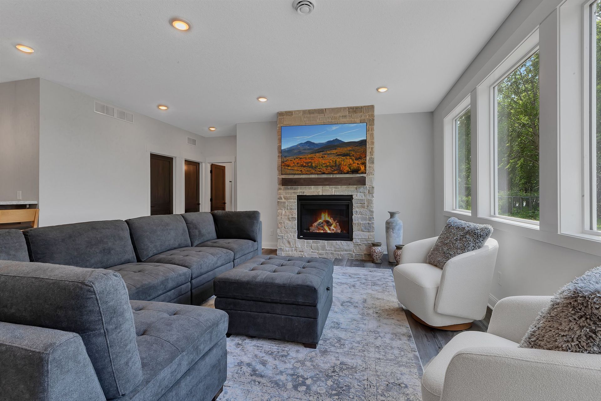 A living room with a couch , chairs , ottoman , fireplace and television.