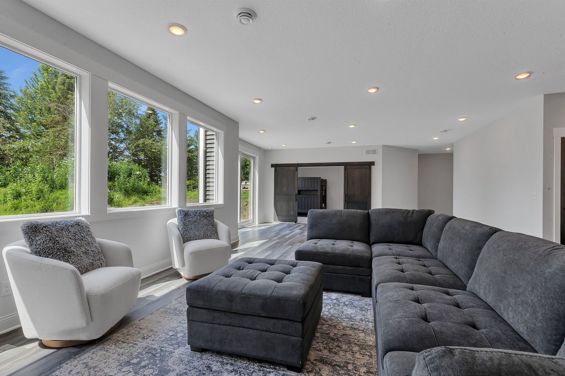 A living room with a large sectional couch , chairs , and ottoman.