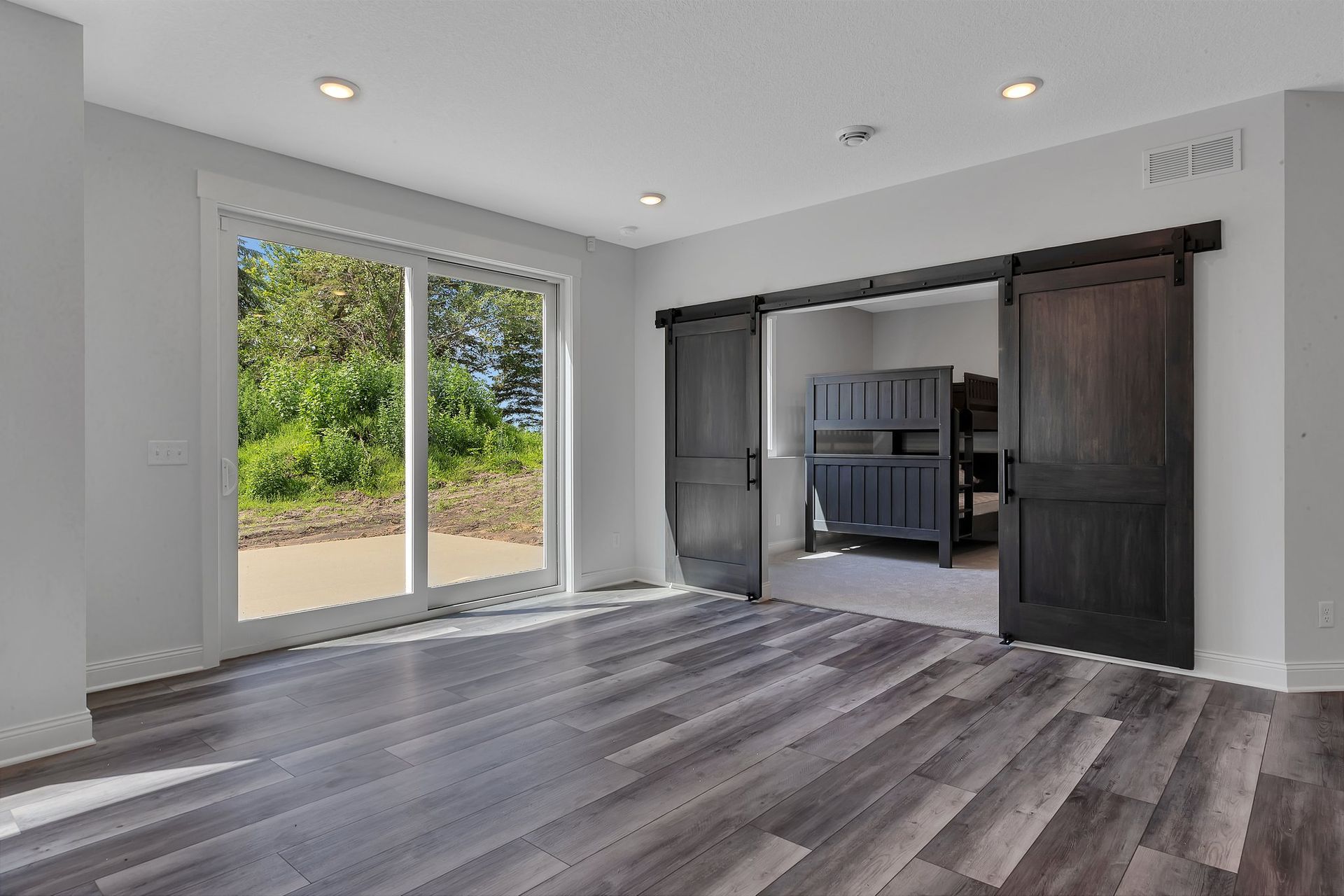 An empty room with sliding barn doors and bunk beds.