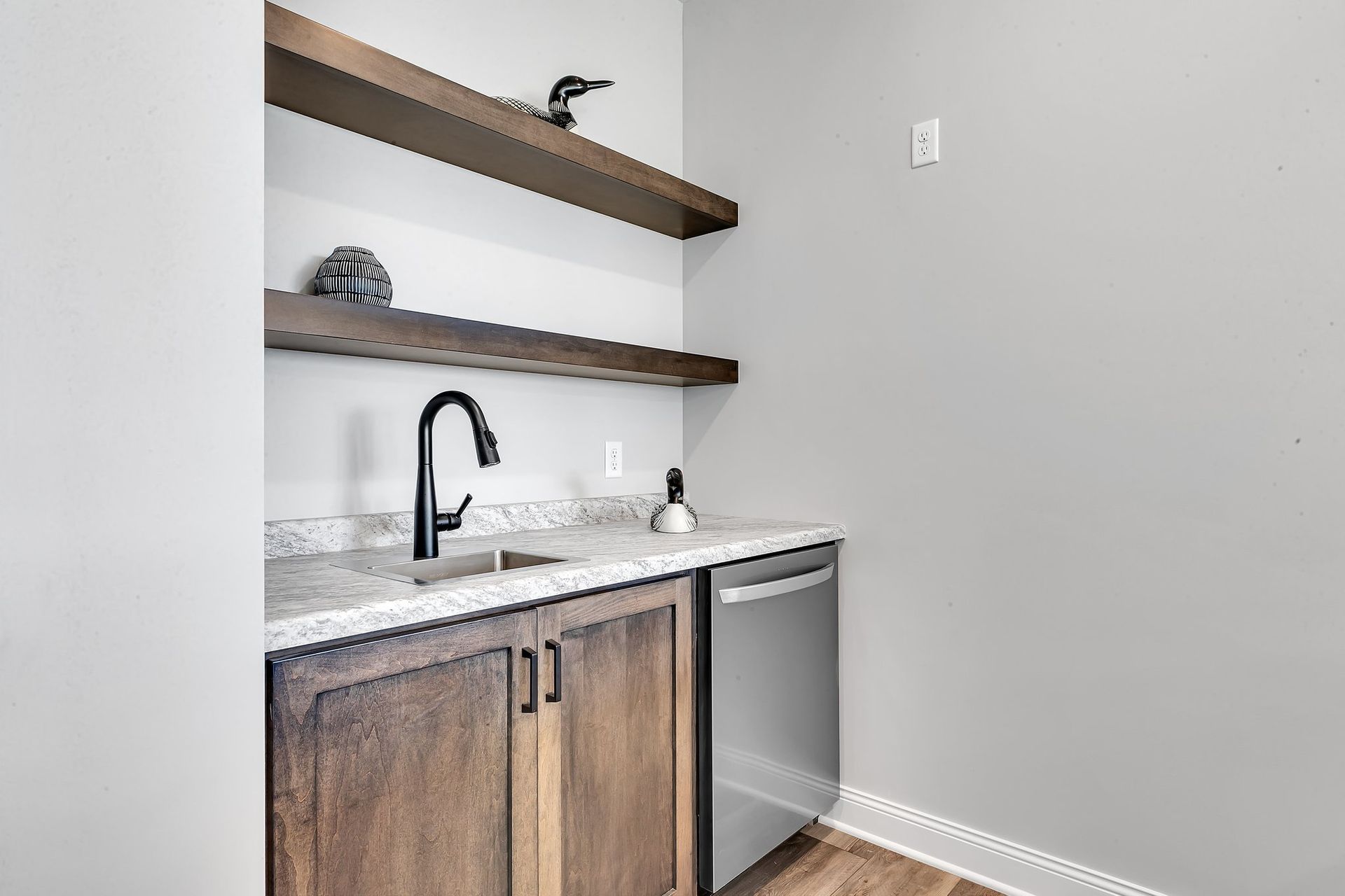 A kitchen with a sink , dishwasher , and shelves.