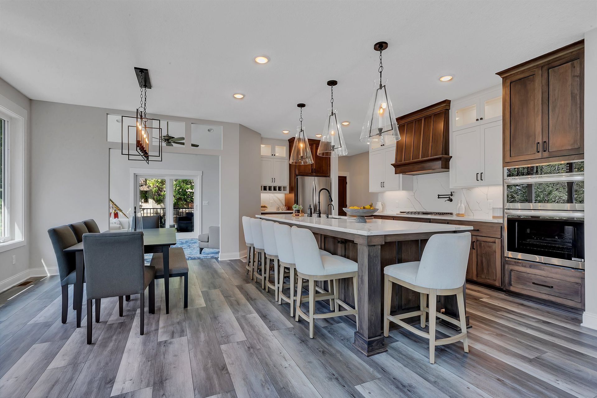 A kitchen with a large island , dining table and chairs.