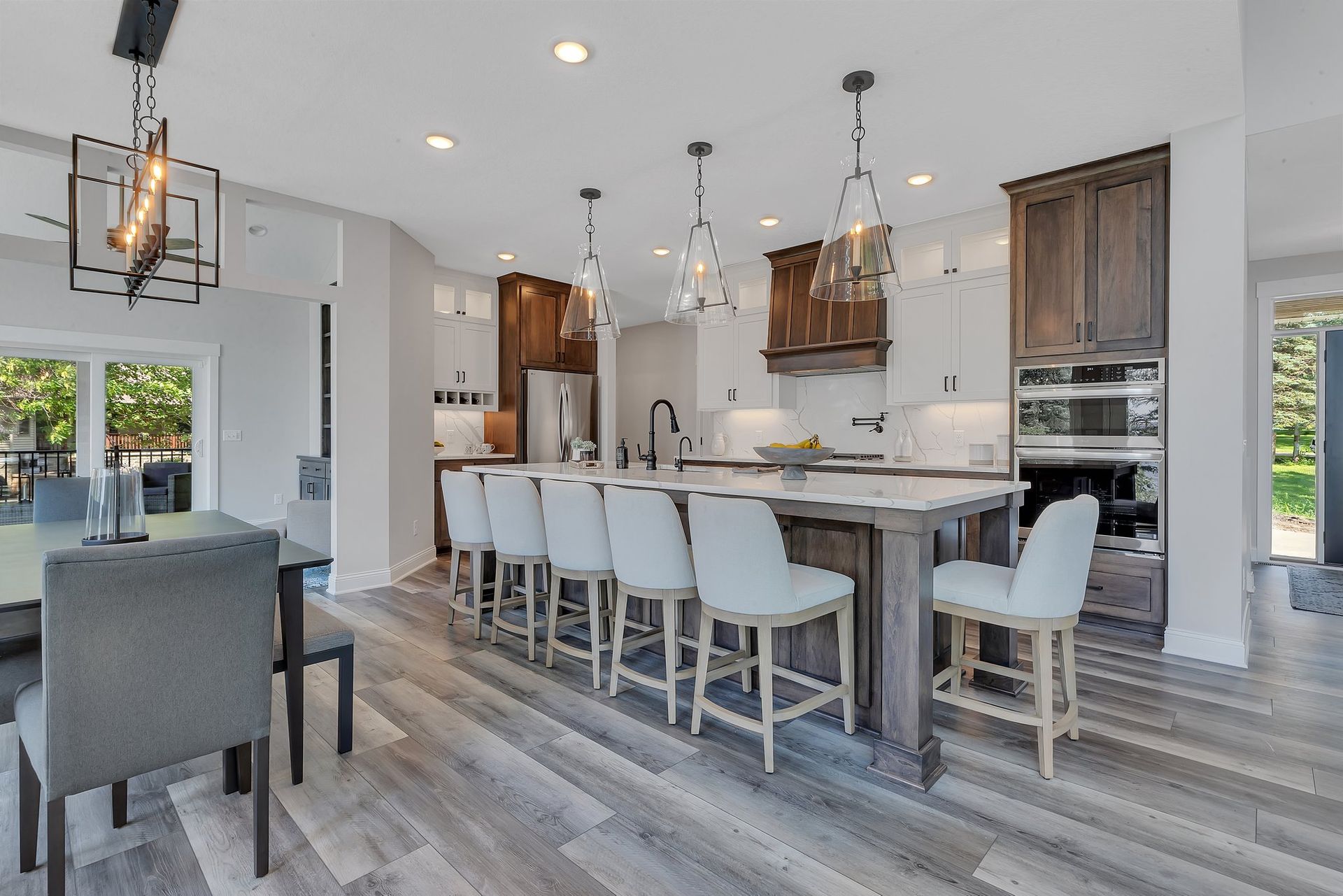 A kitchen with a large island , stools , a table and chairs.
