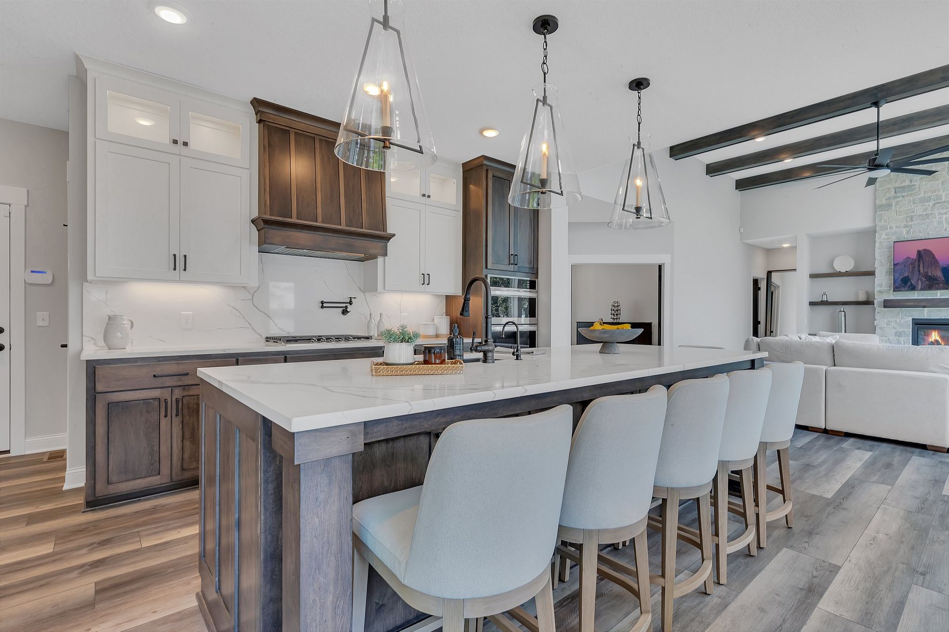 A kitchen with a large island and stools in a house.