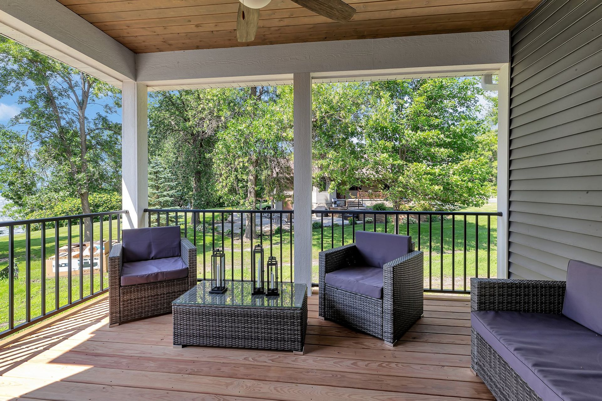 A porch with chairs , a table and a ceiling fan