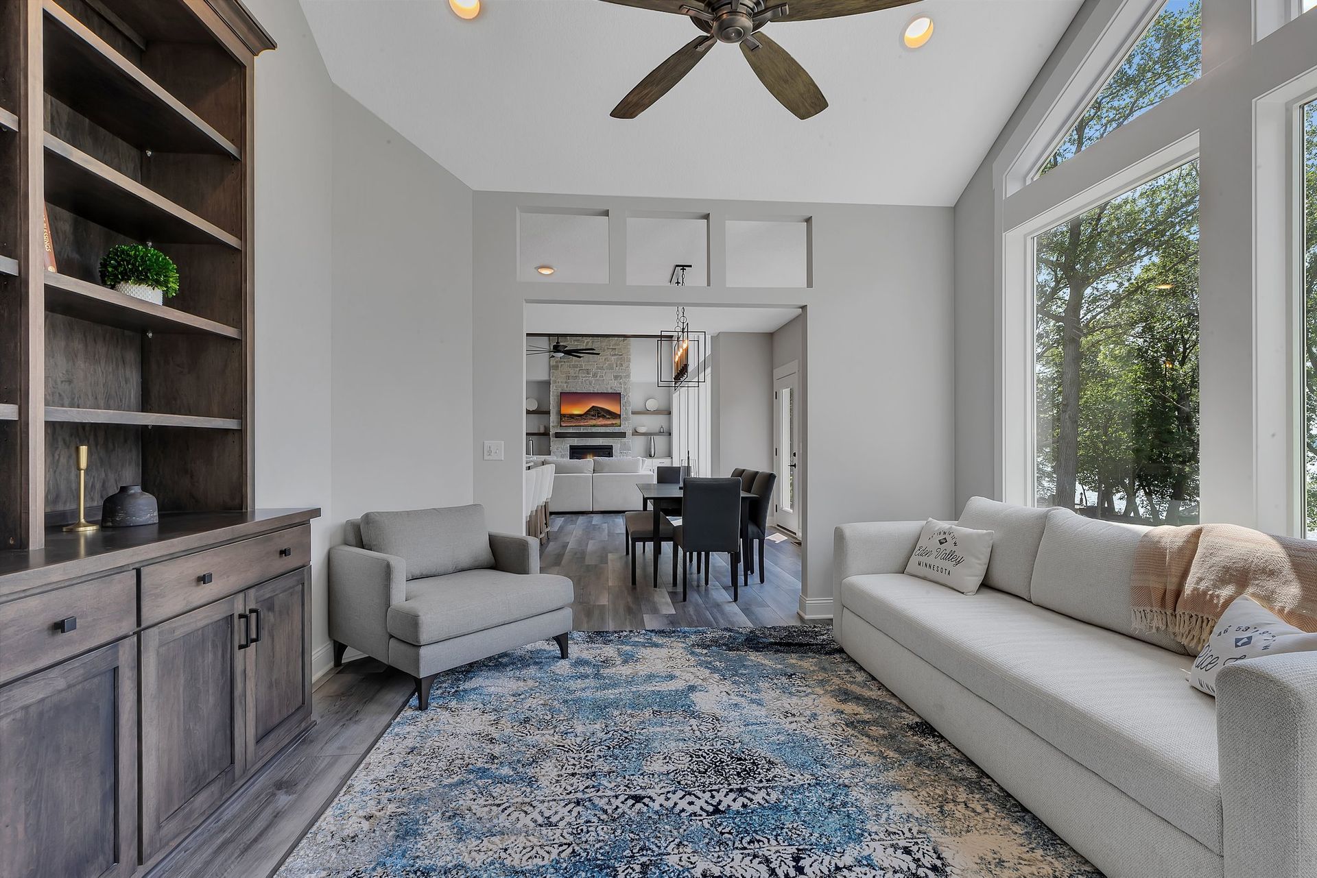 A living room with a couch , chair , rug and ceiling fan.