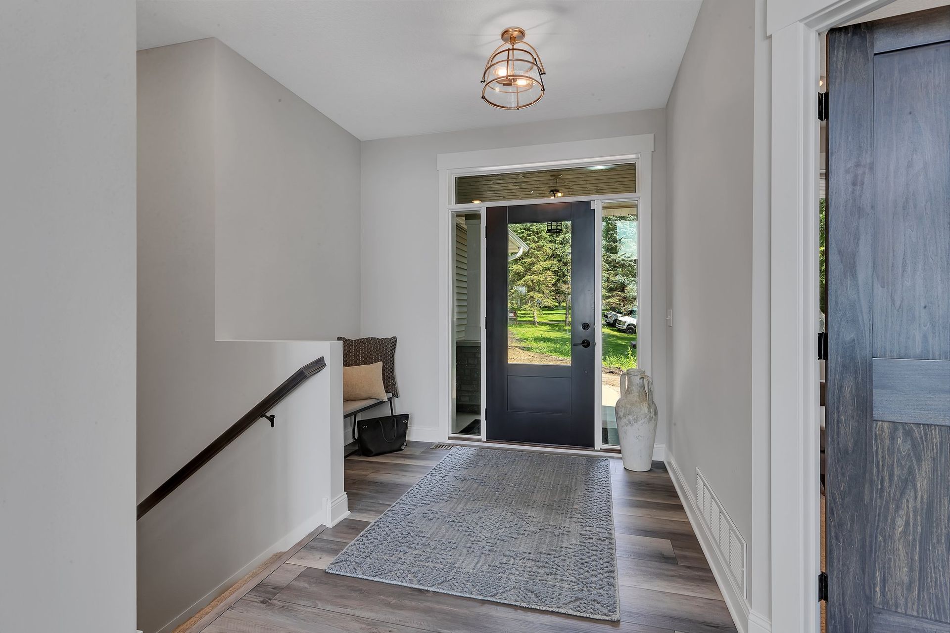 A hallway with a black door and stairs leading up to it.