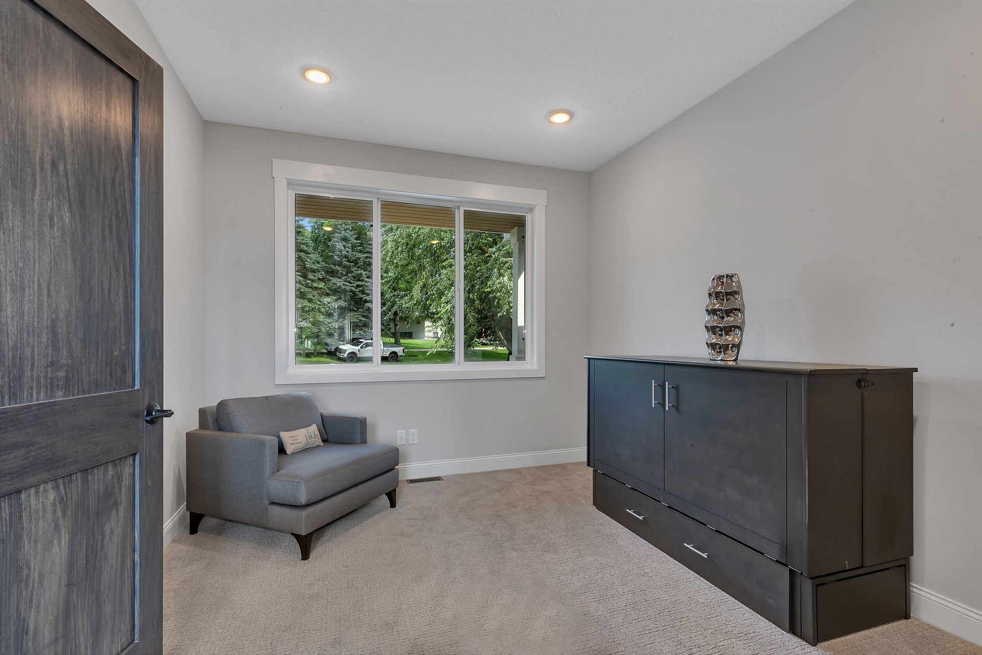 A living room with a chair , dresser , and window.