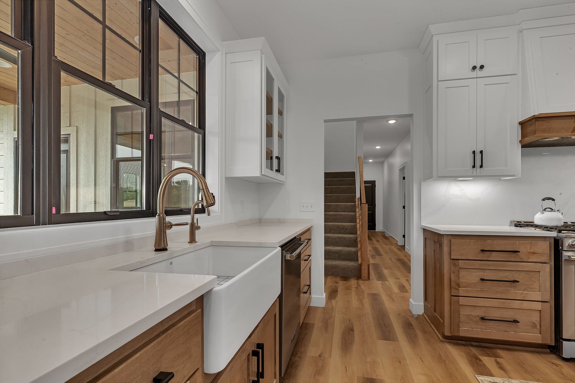 A kitchen with a sink , stove , cabinets and hardwood floors.