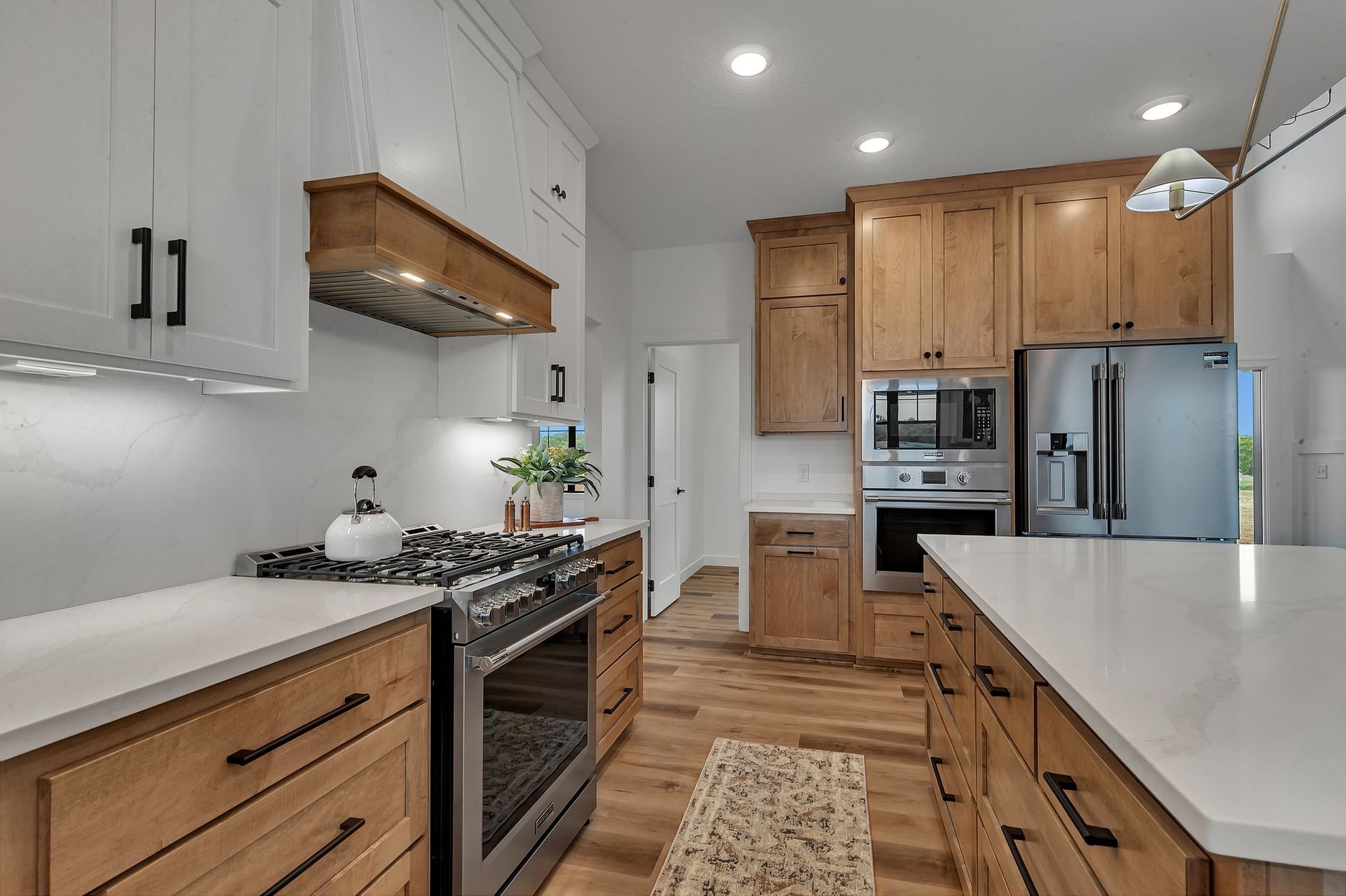 A kitchen with wooden cabinets , stainless steel appliances , and white counter tops.