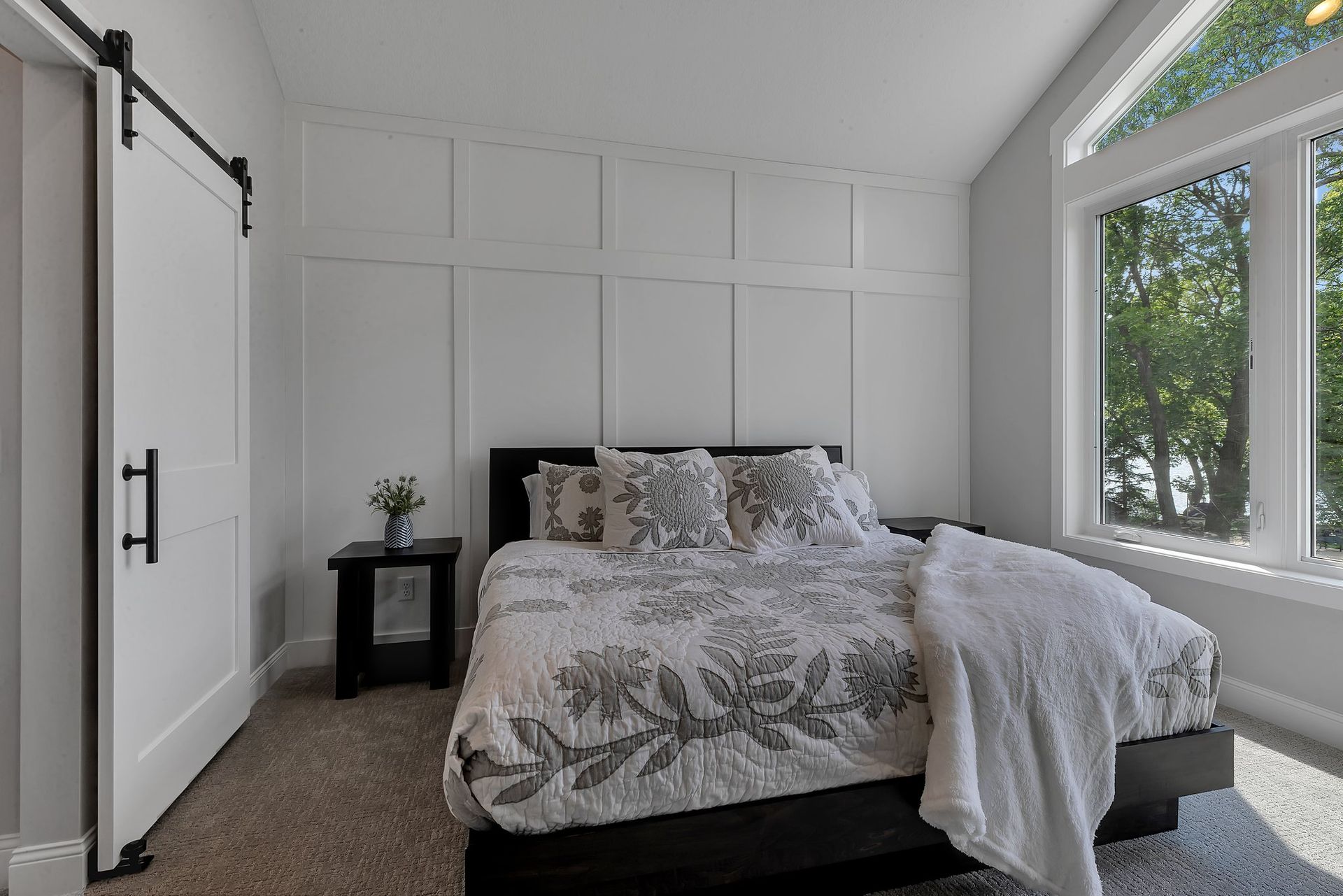 A bedroom with a bed , nightstand , and sliding barn door.