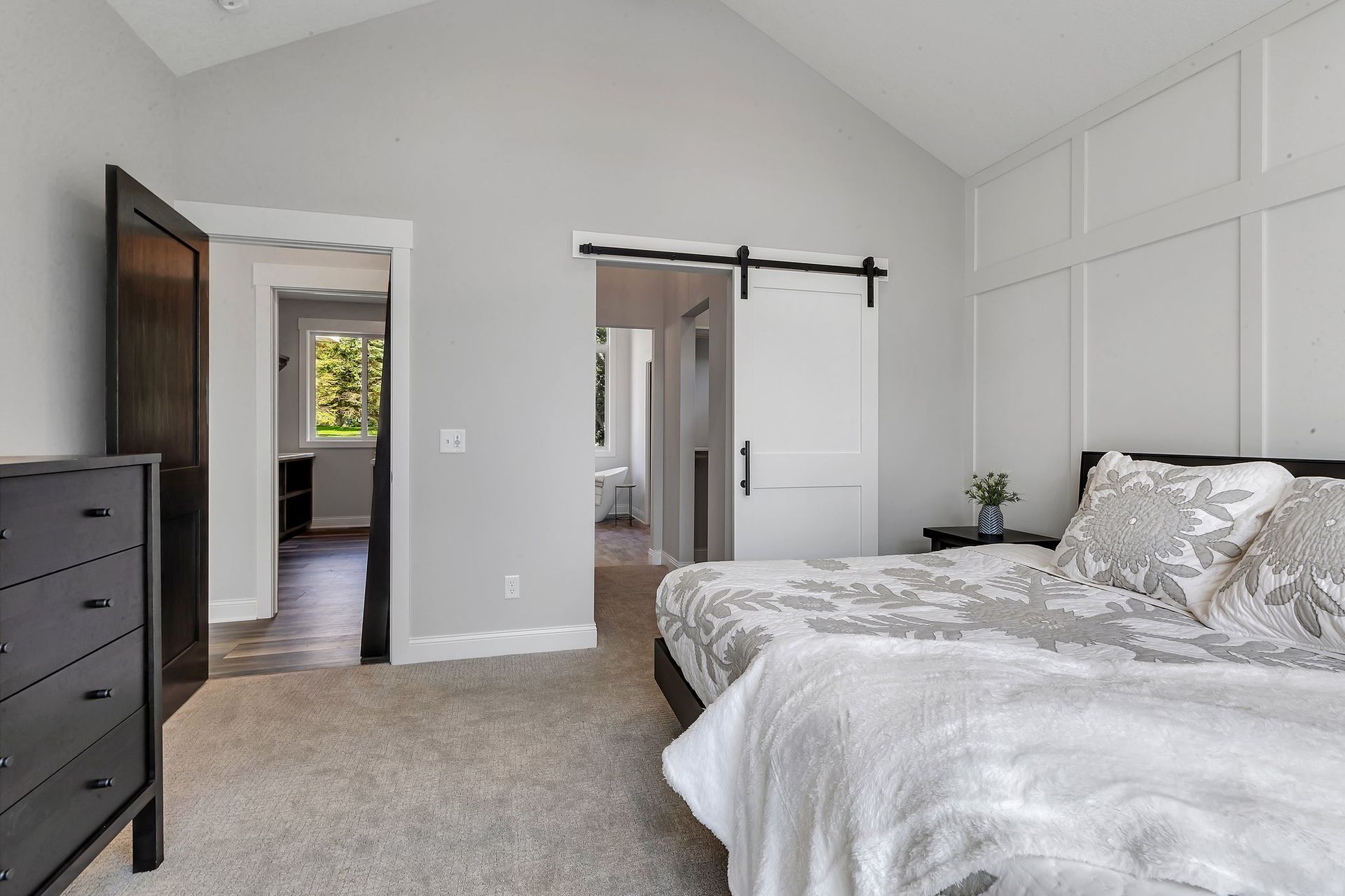 A bedroom with two beds , a dresser , and a sliding barn door.