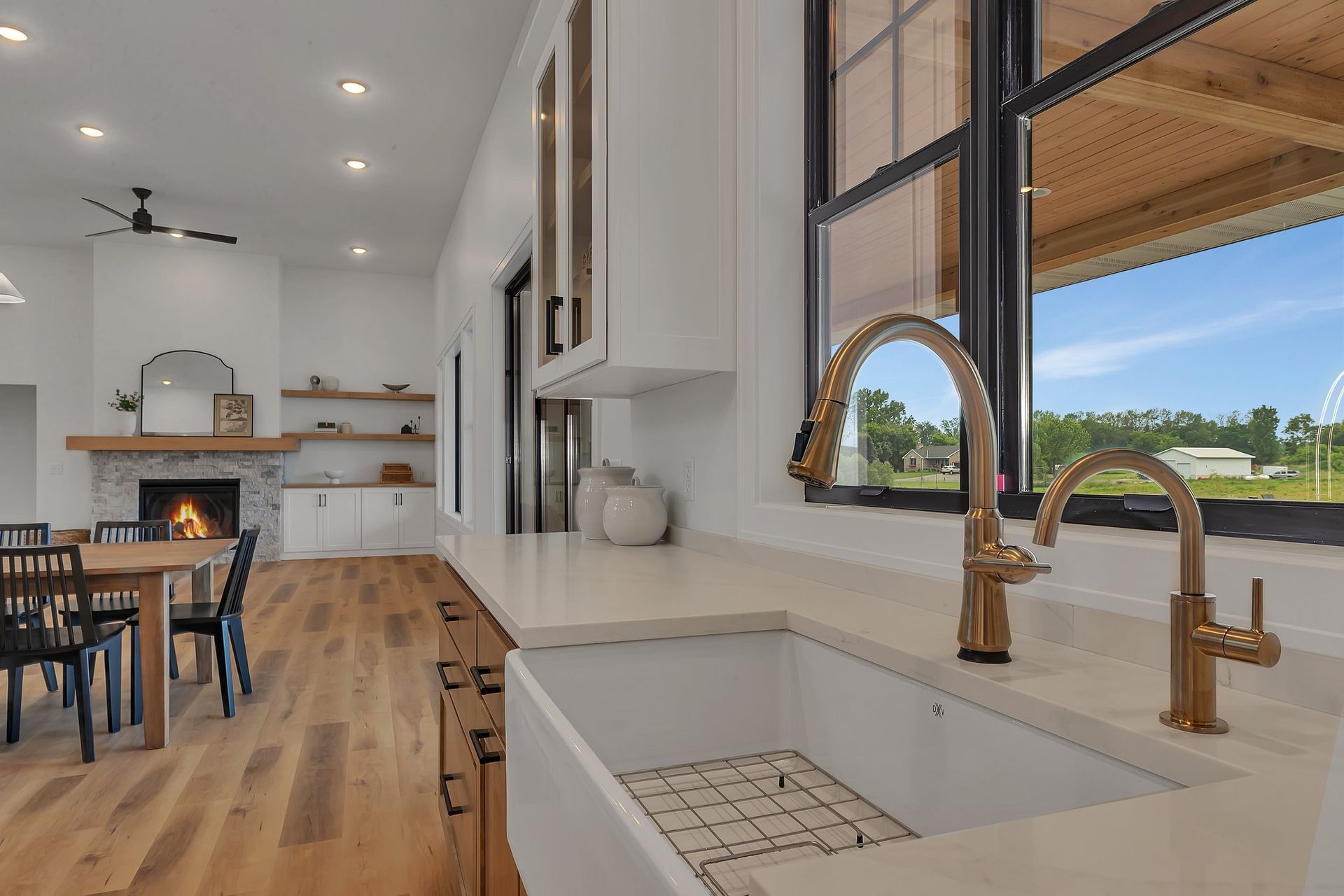 A kitchen with a sink and a window with a view of a field.