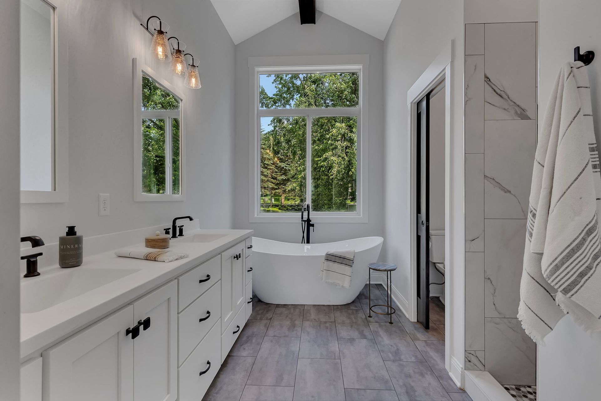 A bathroom with a tub , sinks , mirrors and a window.