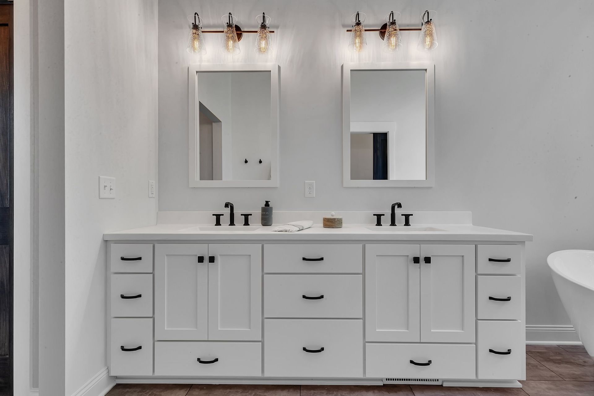 A bathroom with two sinks , two mirrors , and a bathtub.