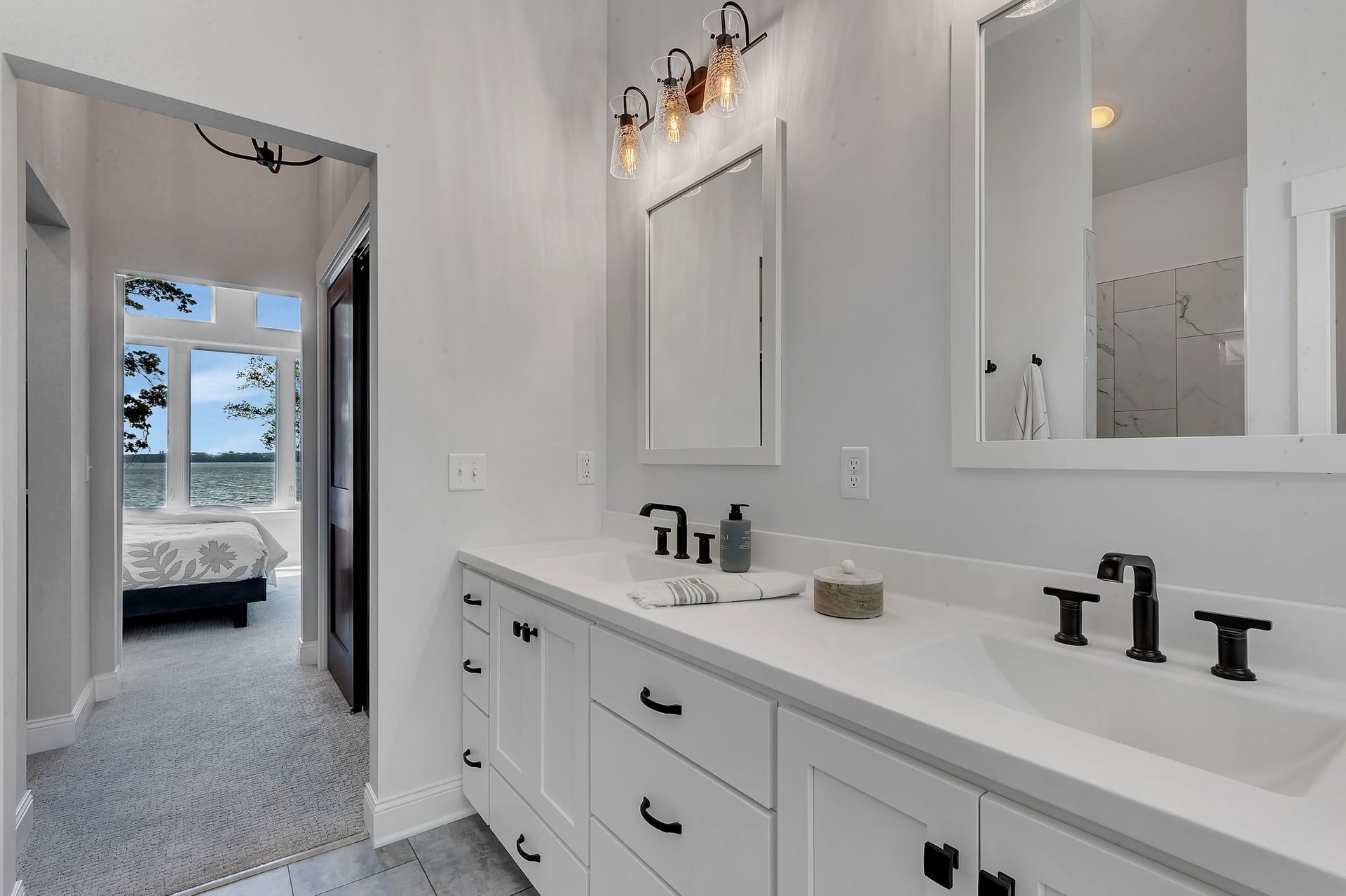 A bathroom with two sinks , two mirrors and a walk in shower.