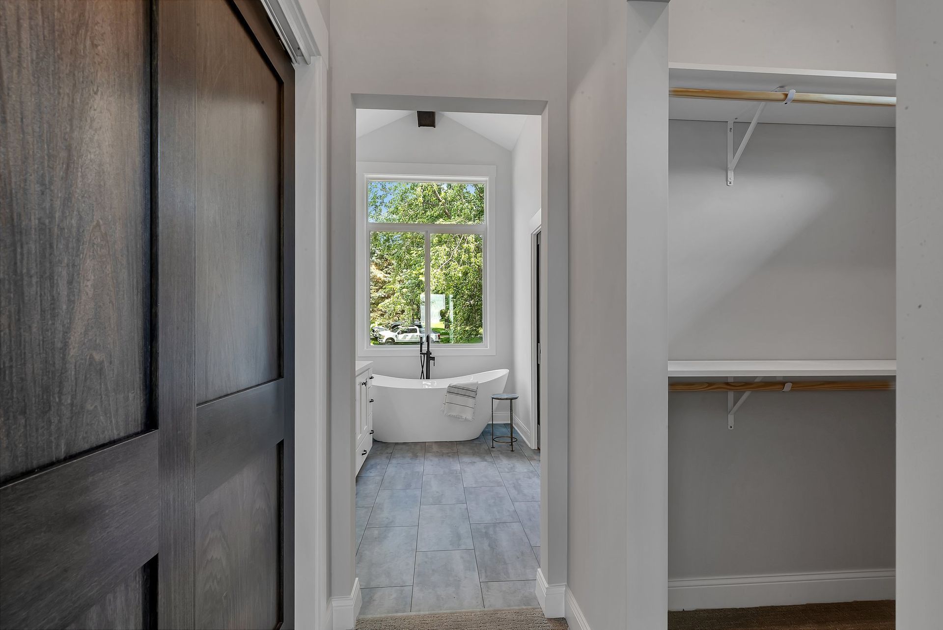 A hallway leading to a bathroom with a tub and a window.