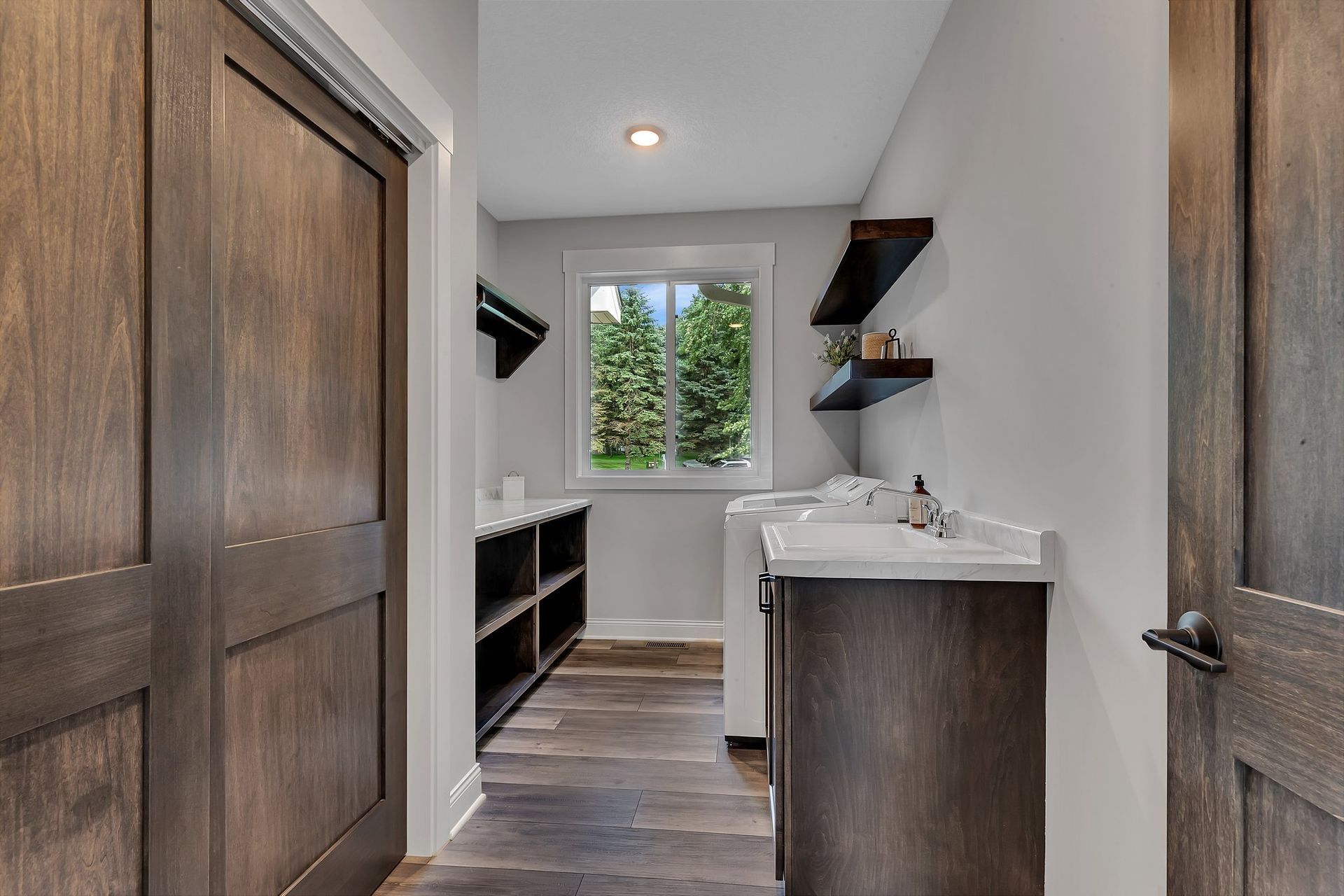 A laundry room with a sink , washer and dryer , and a window.