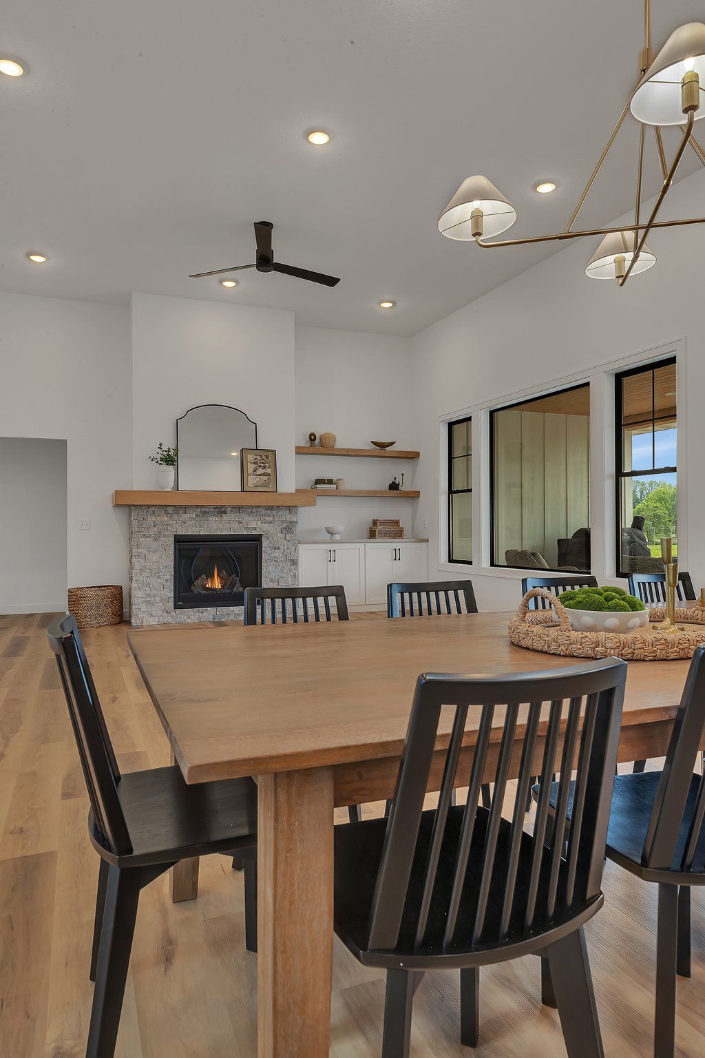 A dining room with a wooden table and chairs and a fireplace.