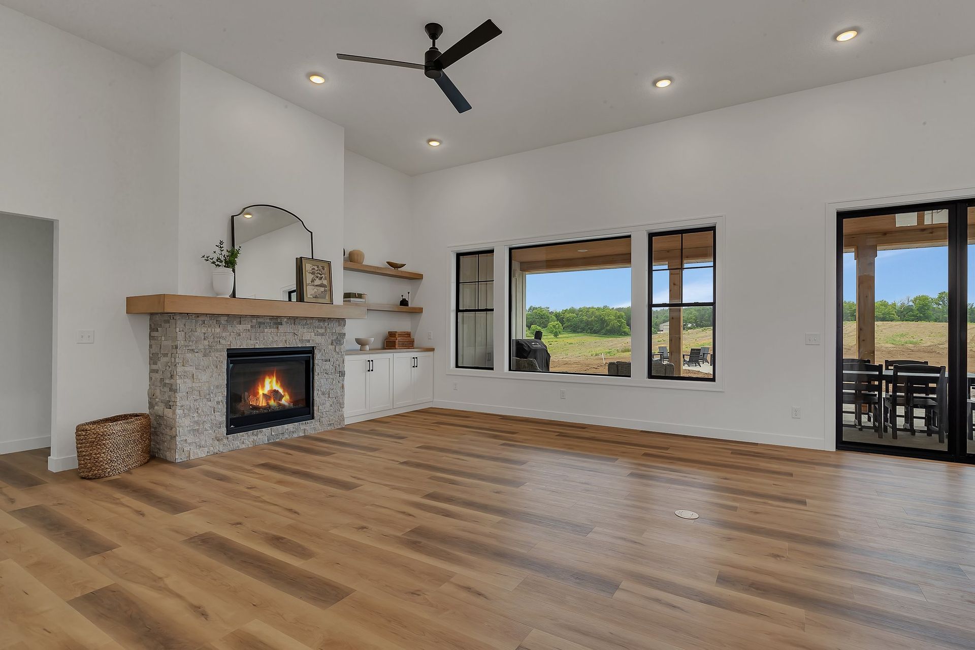 A living room with hardwood floors , a fireplace and a ceiling fan.