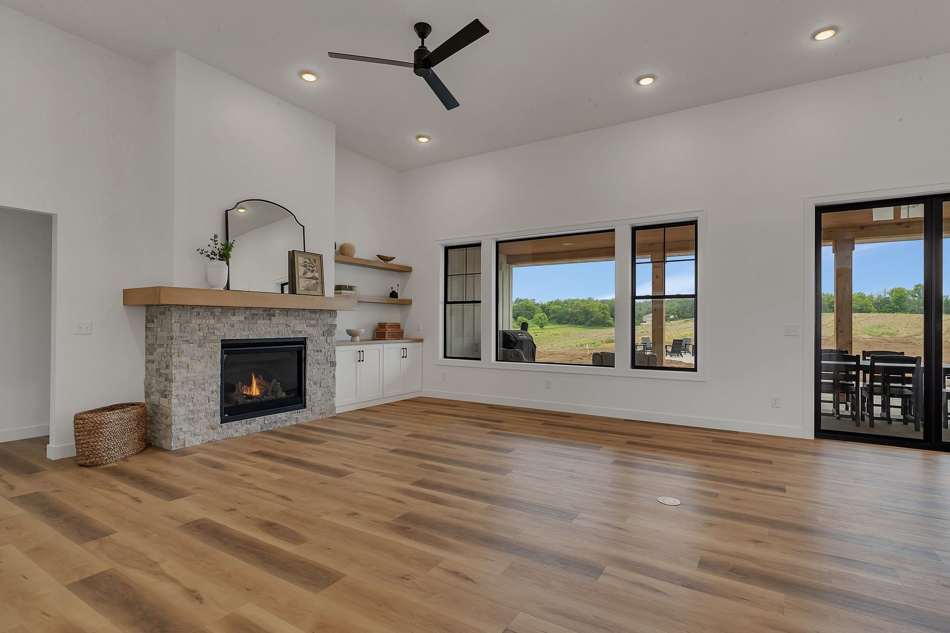A living room with hardwood floors , a fireplace and a ceiling fan.