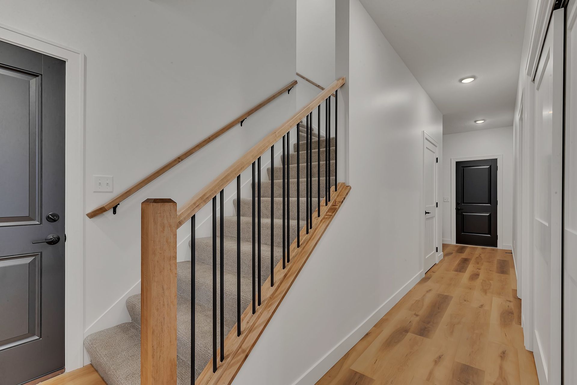 A hallway with stairs and a wooden railing